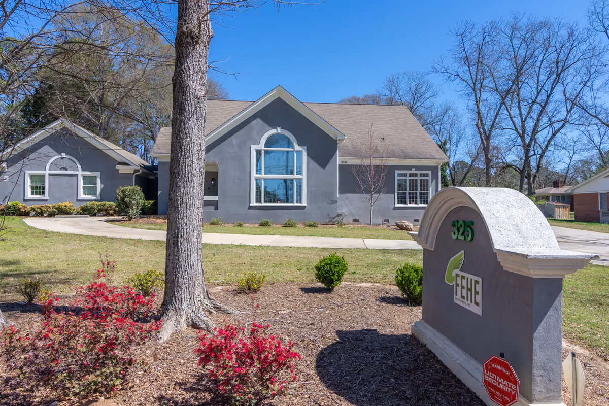 Exterior view of Fehe Private Healthcare Services building with a landscaped front yard and sign.