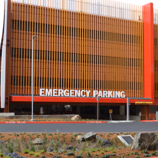 Exterior view of a building facade with vertical wooden slats and Emergency Parking sign.
