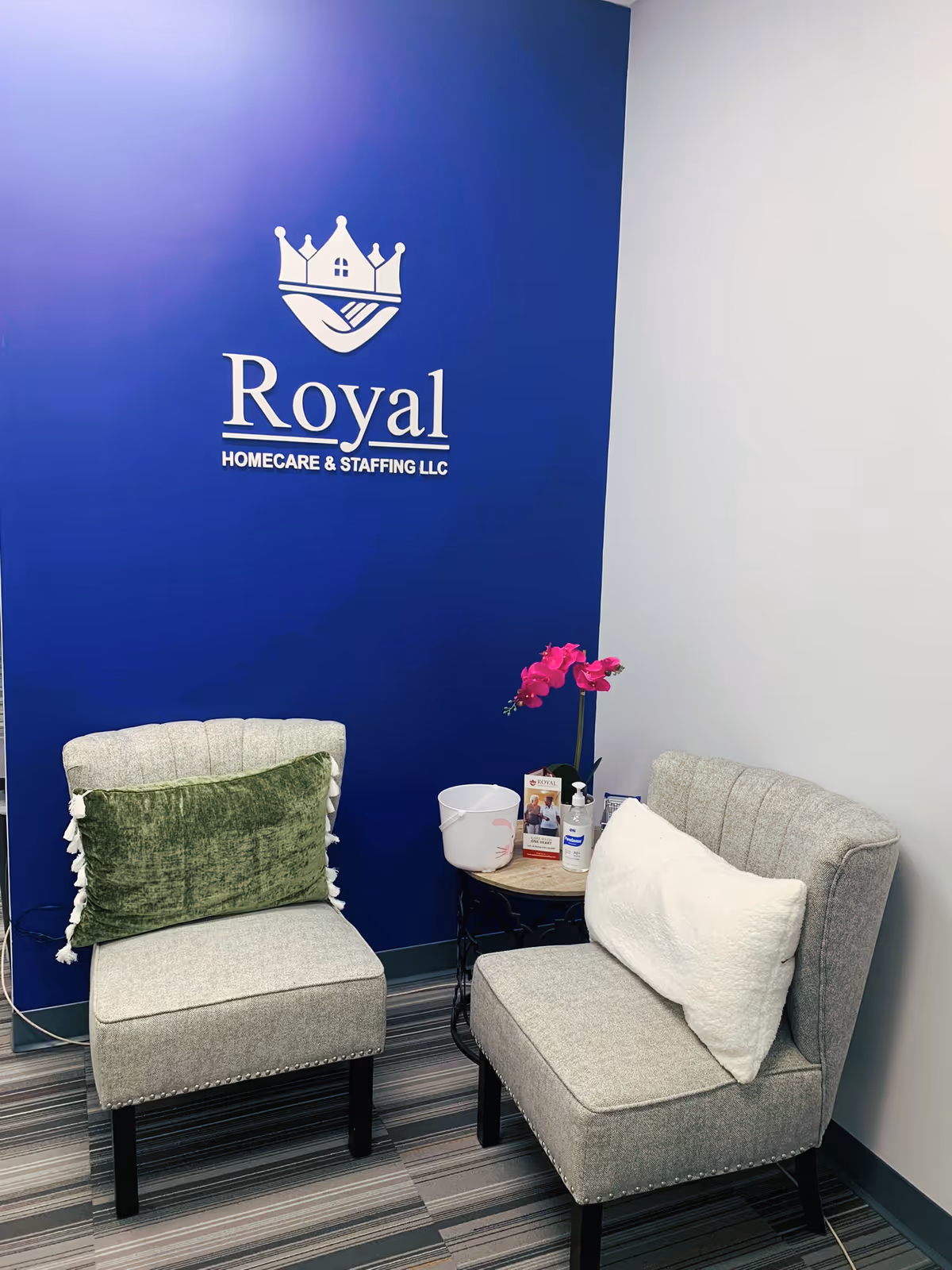 Royal logo on blue wall with two gray chairs and a small table with an orchid.