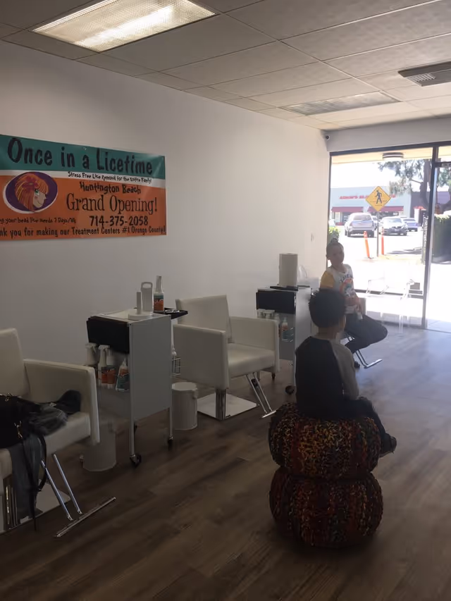 Interior of a treatment center with white chairs, carts, and a bright banner on the wall.