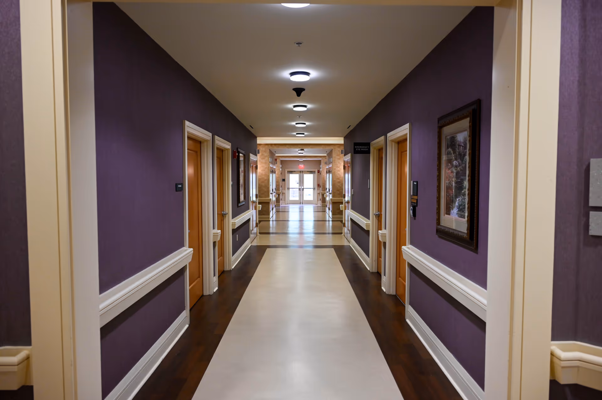 Interior hallway of a senior living facility with purple walls and doors.