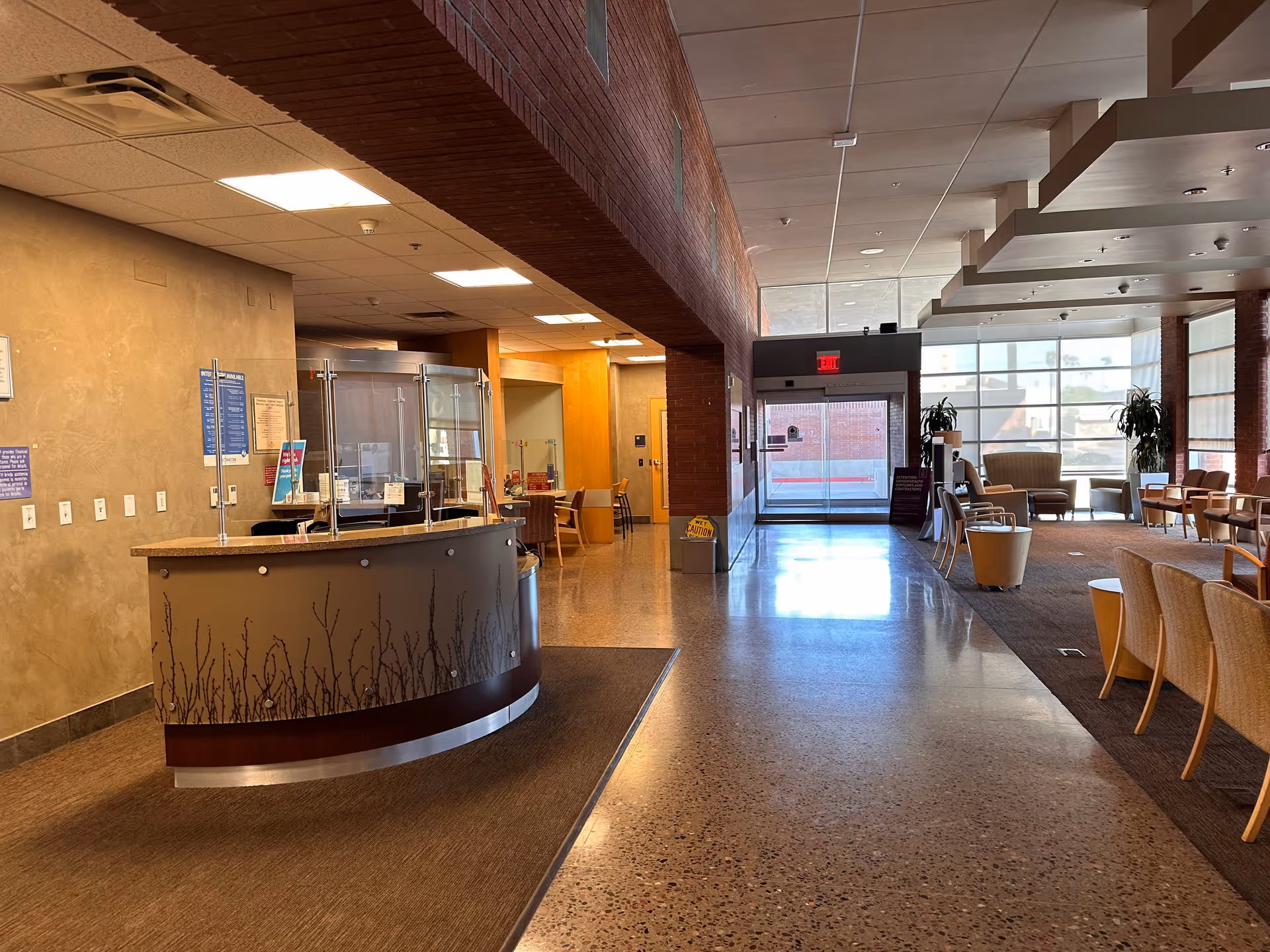 Interior hospital lobby with curved reception desk, seating area, and glass entry.