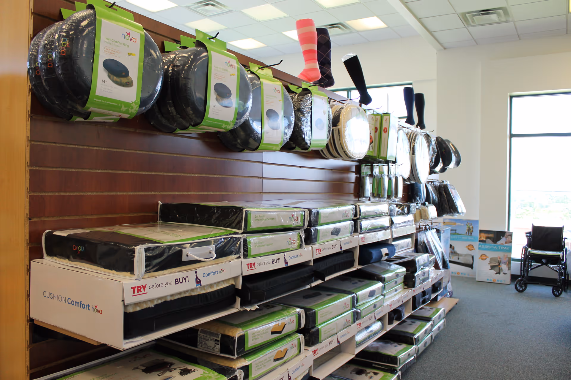 Interior showroom with stacked cushions and bedding on shelves, plus a wheelchair by the window.