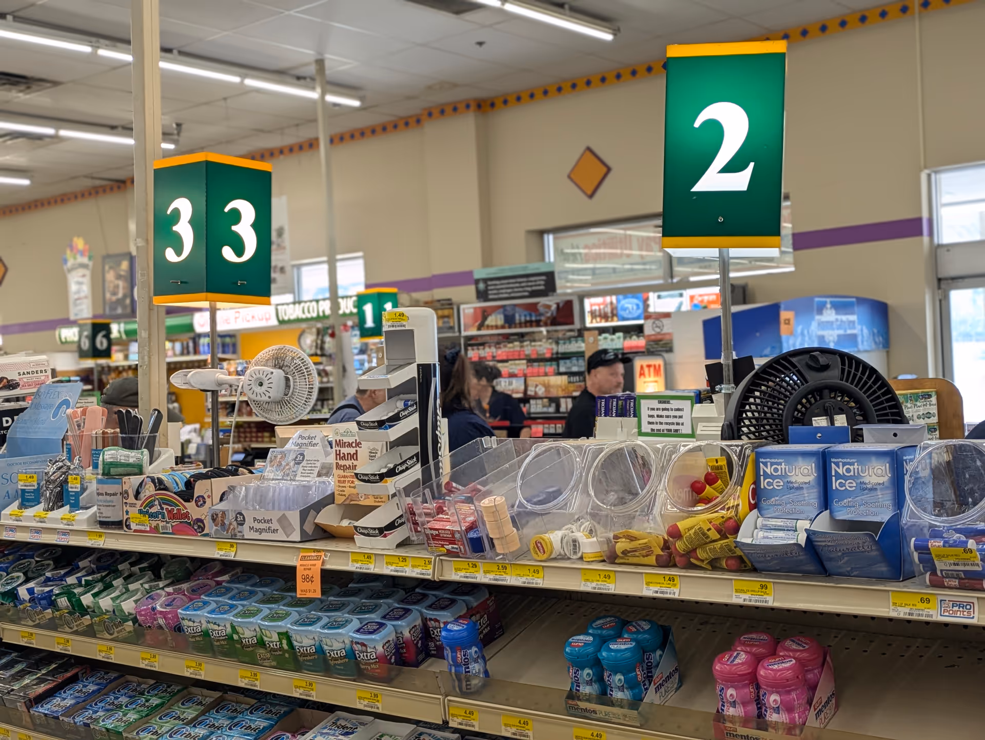 Inside a Discount Drug Mart, checkout counters with bulk items and numbered signs 3 and 2