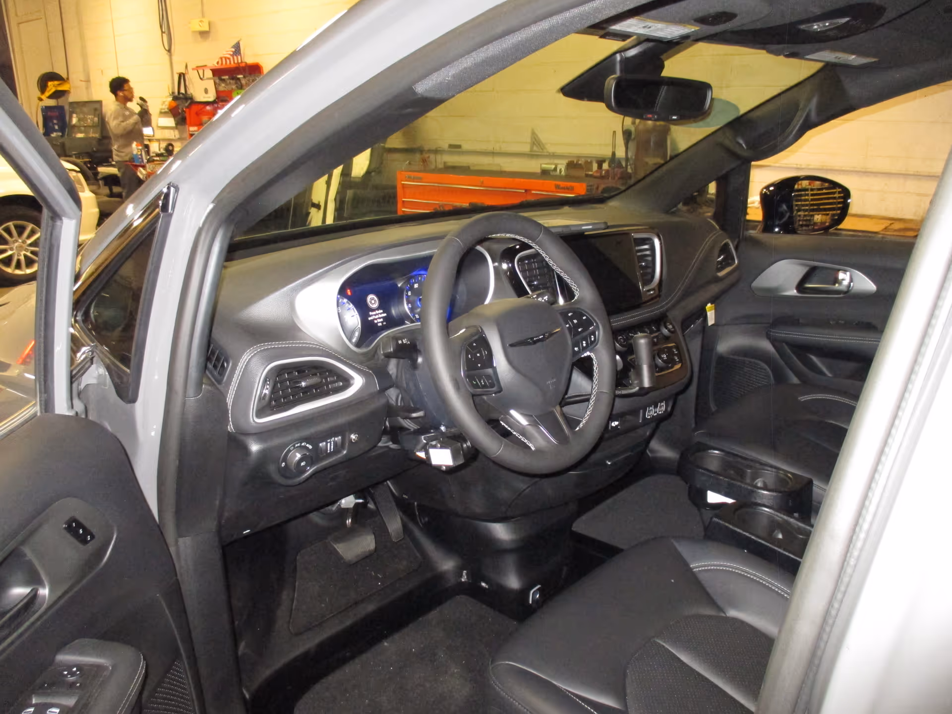 View of a car interior showing steering wheel, dashboard, and front seats.