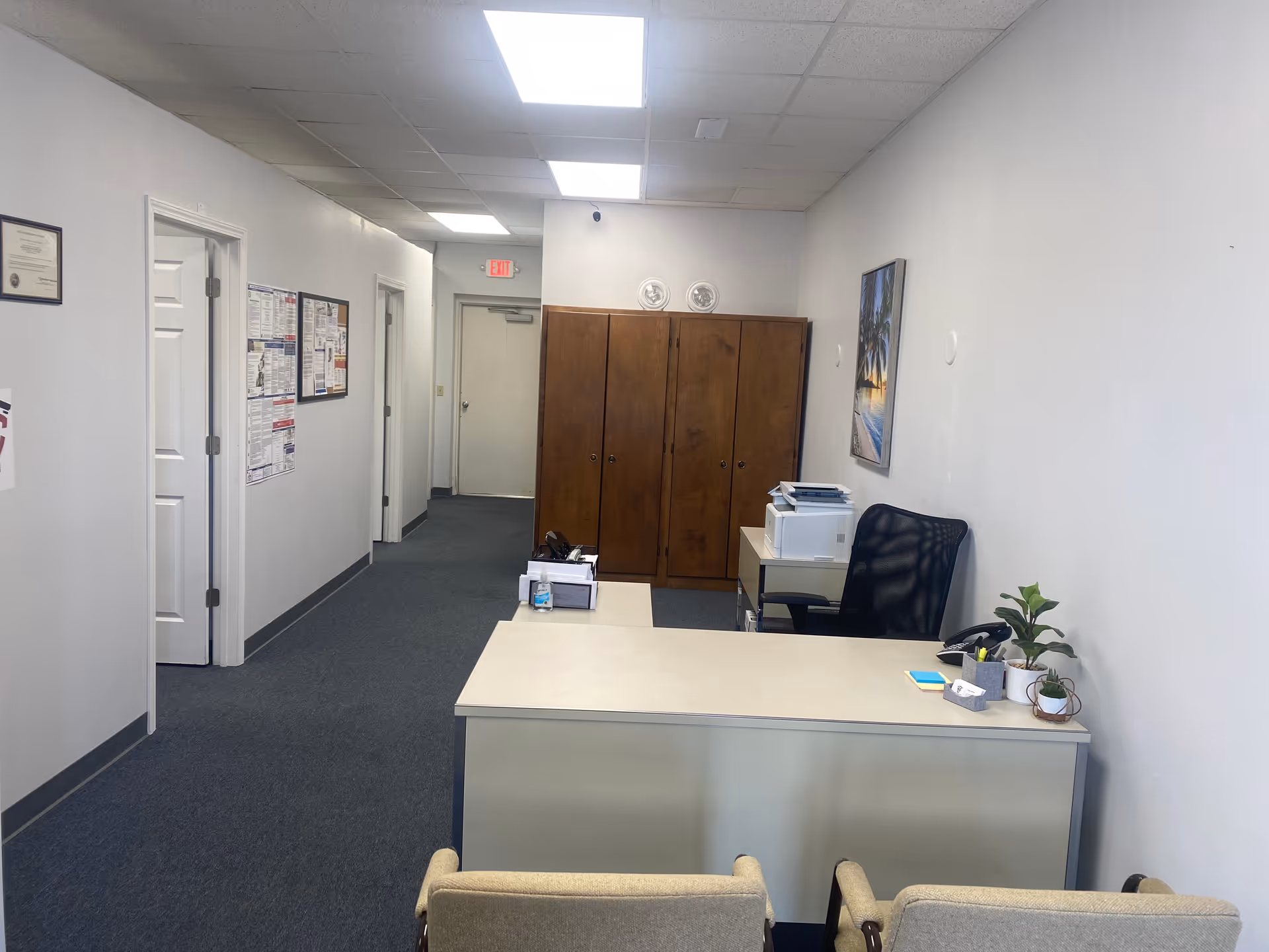 Reception desk in a hallway of a senior care facility with chairs and cabinets.
