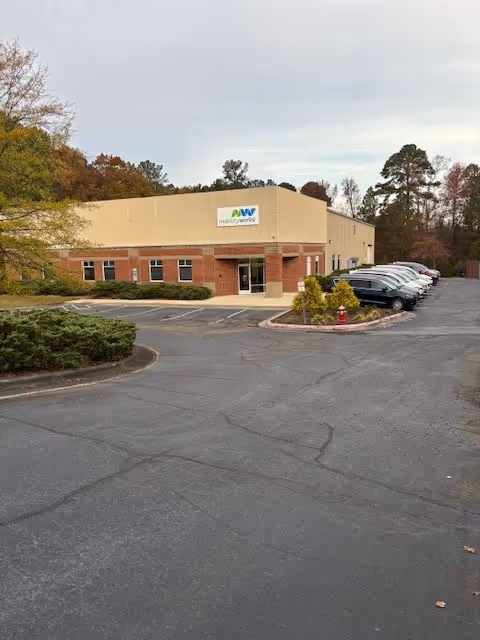 Exterior view of a MobilityWorks facility building with a parking lot and autumn trees.
