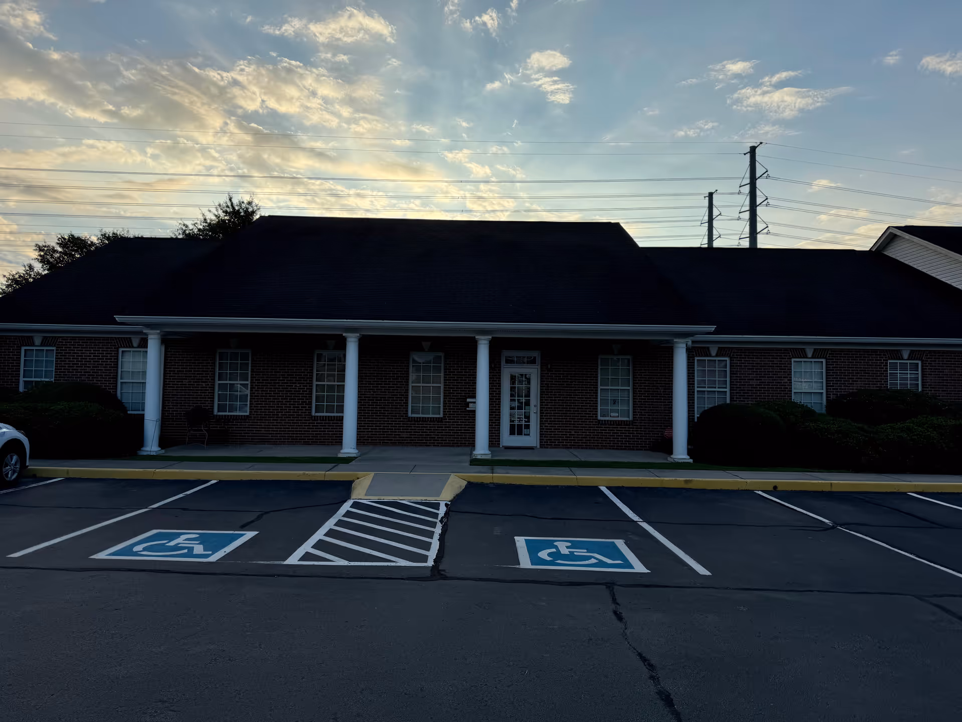 Brick senior living facility exterior with columns and handicapped parking in front.