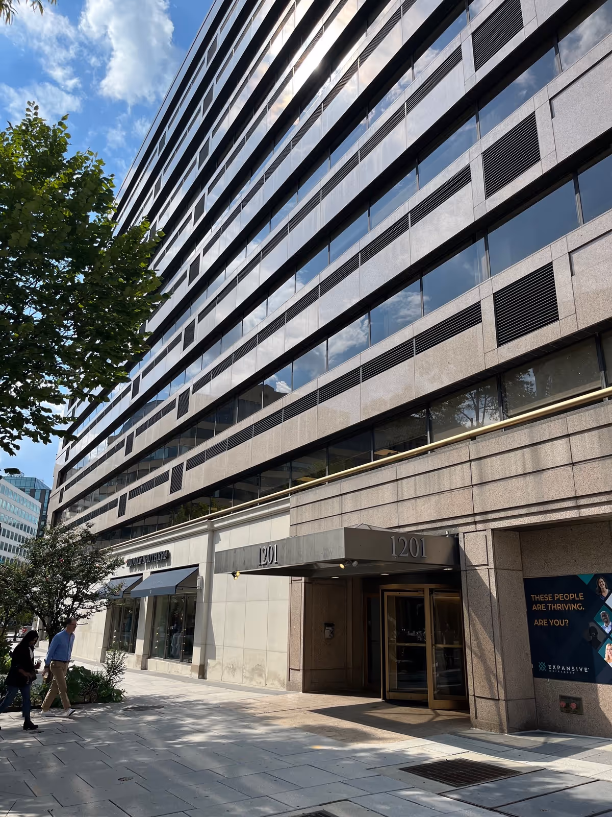 Tall modern office-style building exterior with glass windows and a pedestrian entrance.