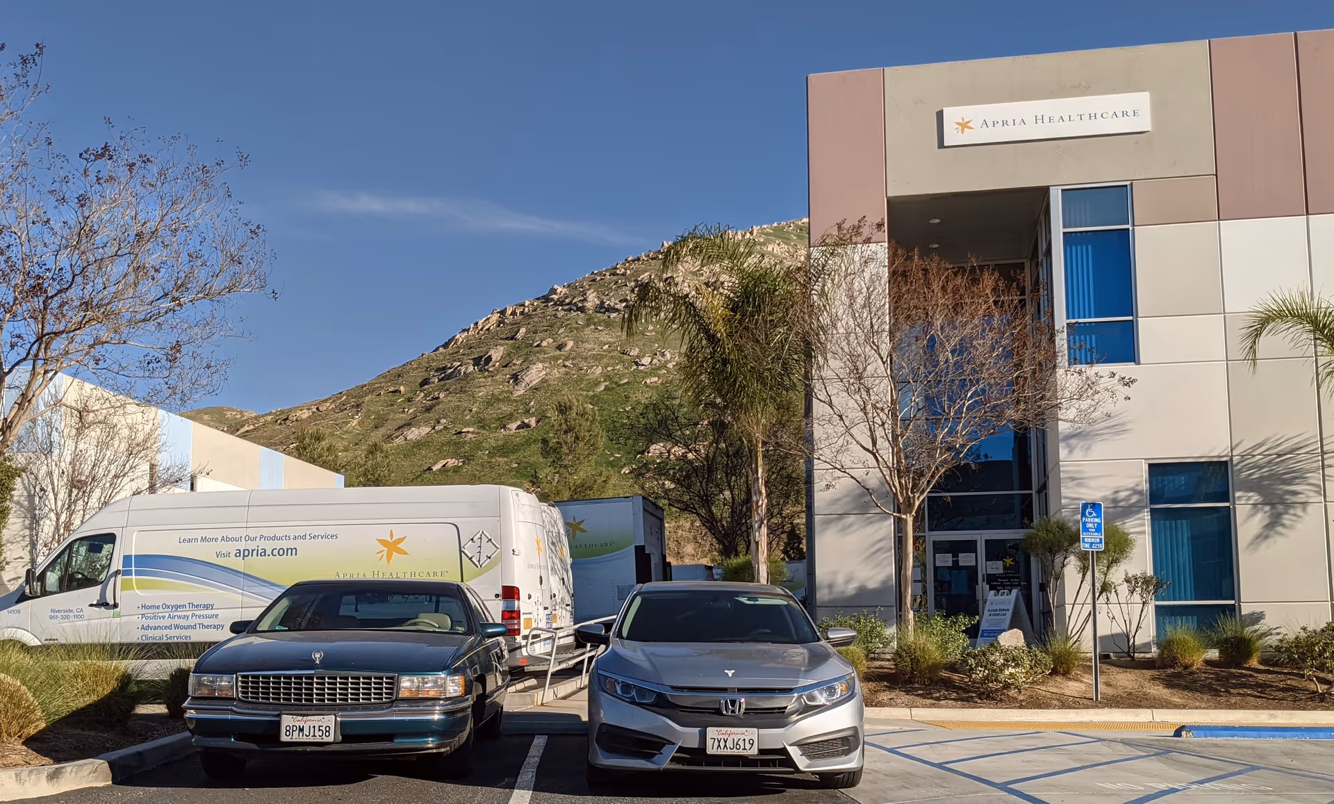 Exterior view of Apria Healthcare building with parked service vans.