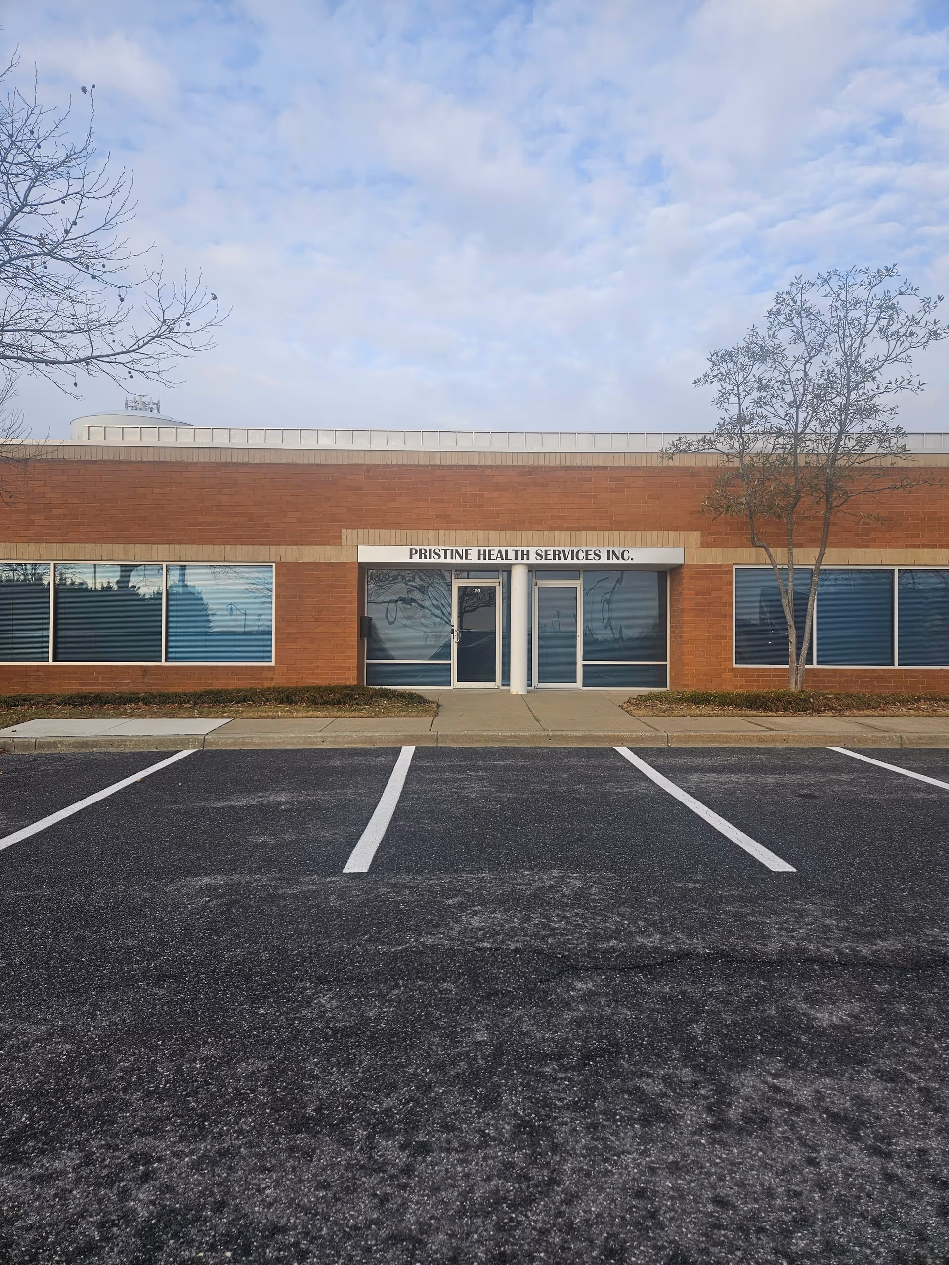 Brick commercial building with glass entrance and Pristine Health Services Inc. sign.
