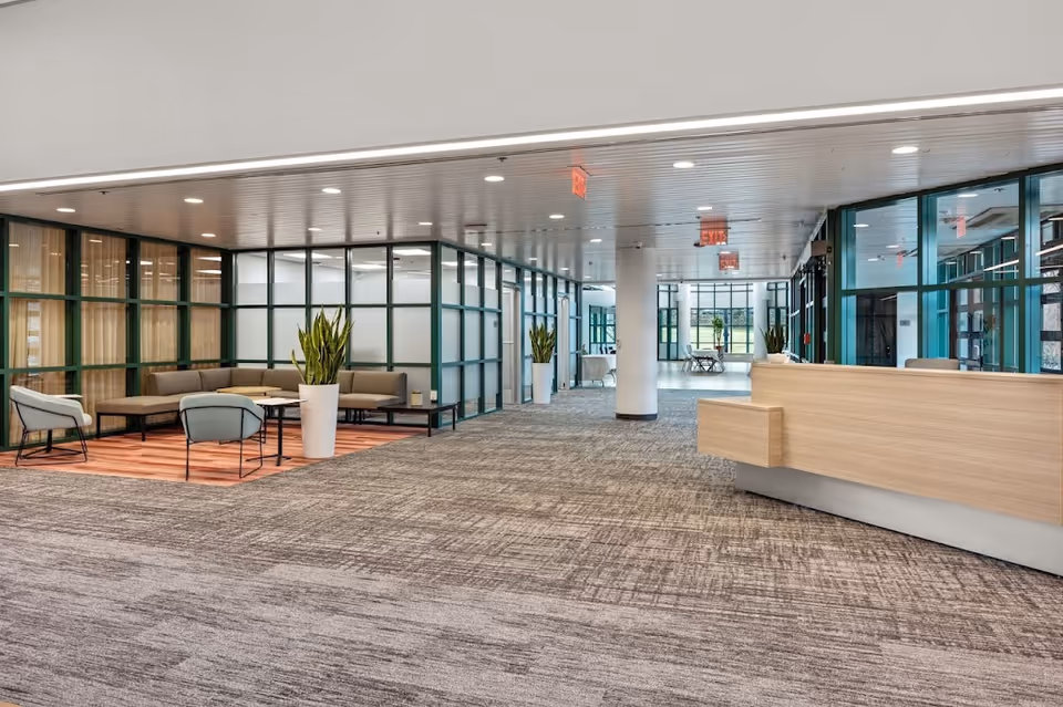 Spacious modern facility lobby with seating areas, glass partitions, and a reception desk.
