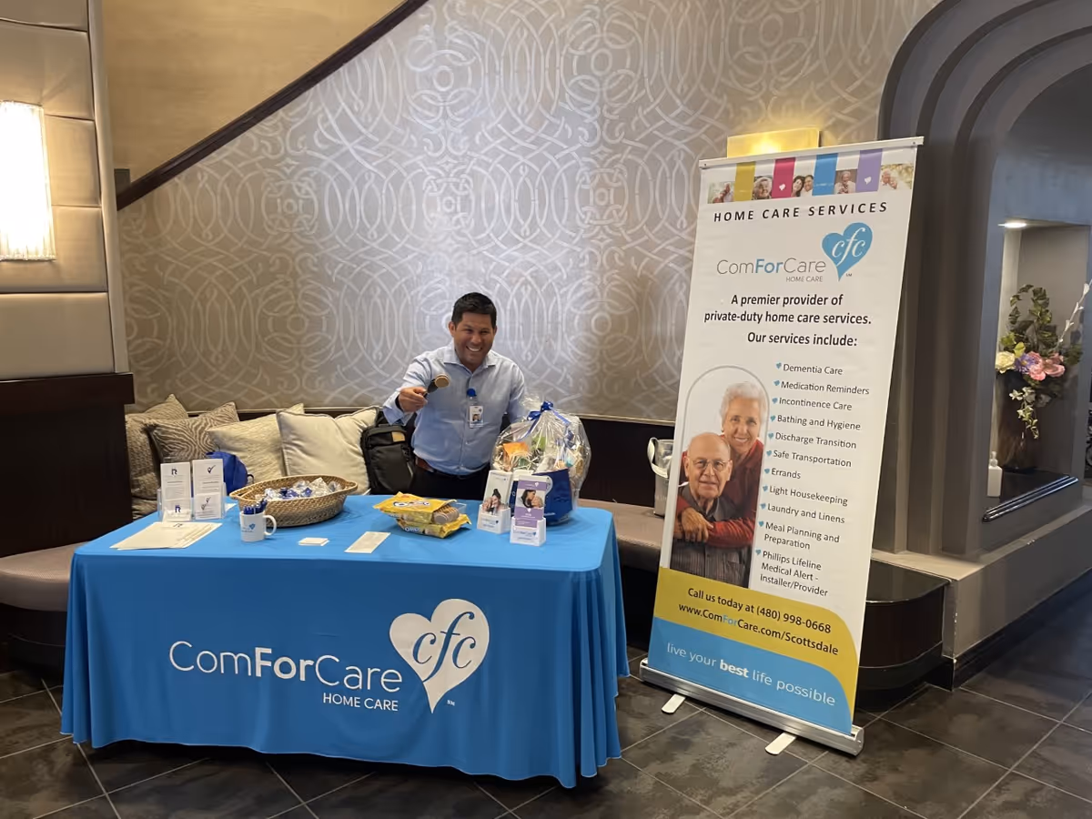 Staff at a ComForCare booth with banners in a lobby area.