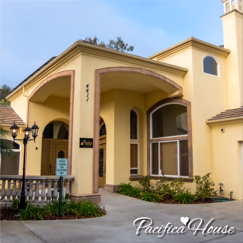 Exterior view of Pacifica House building with arched entrance and landscaping.