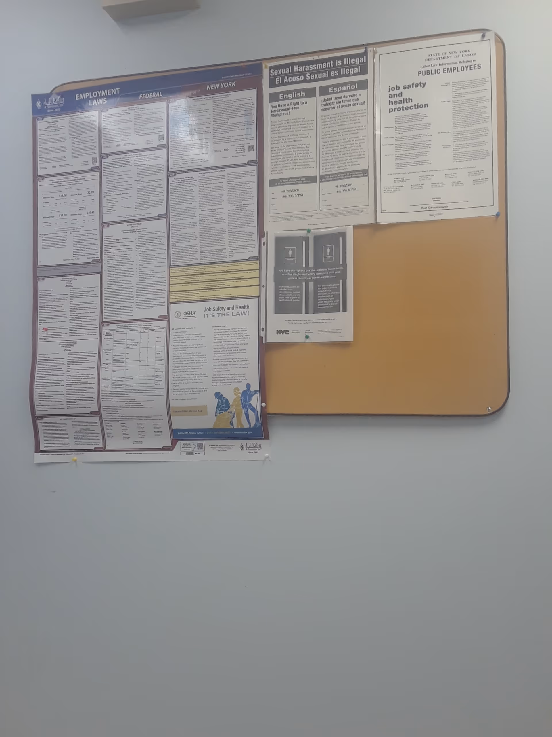 Interior wall with bulletin boards displaying employment and safety notices.