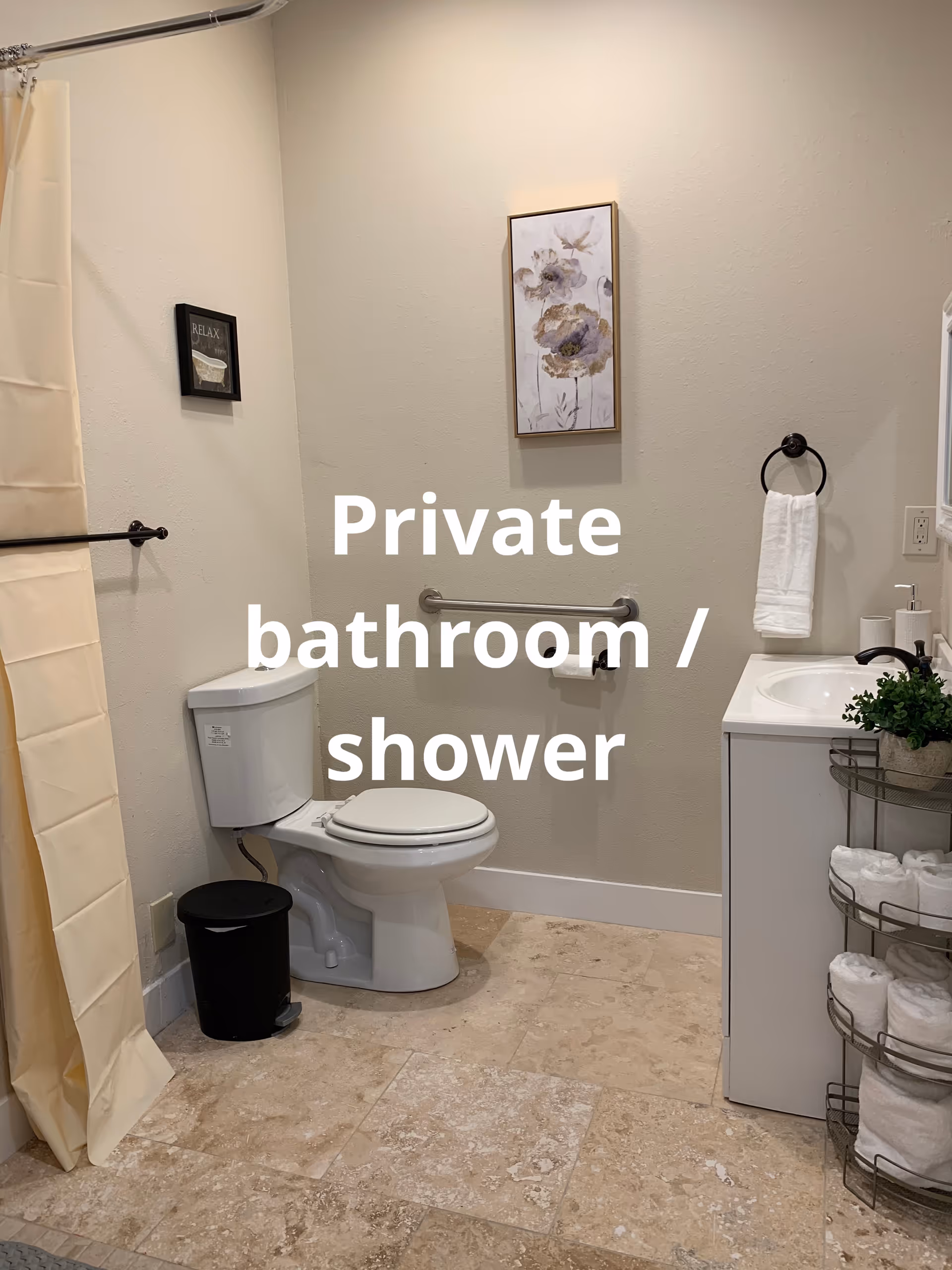 Private bathroom with toilet, sink, shower curtain, towels, and framed art.