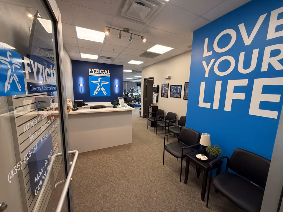Reception area inside FYZICAL Therapy lobby with blue branding and seating.