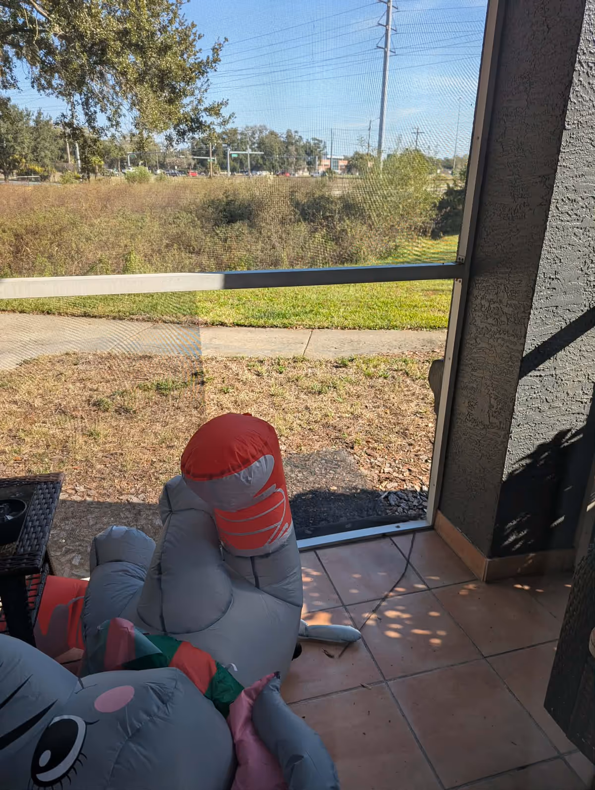 Indoor covered patio with inflatable toys on a tiled floor and outdoor view through glass
