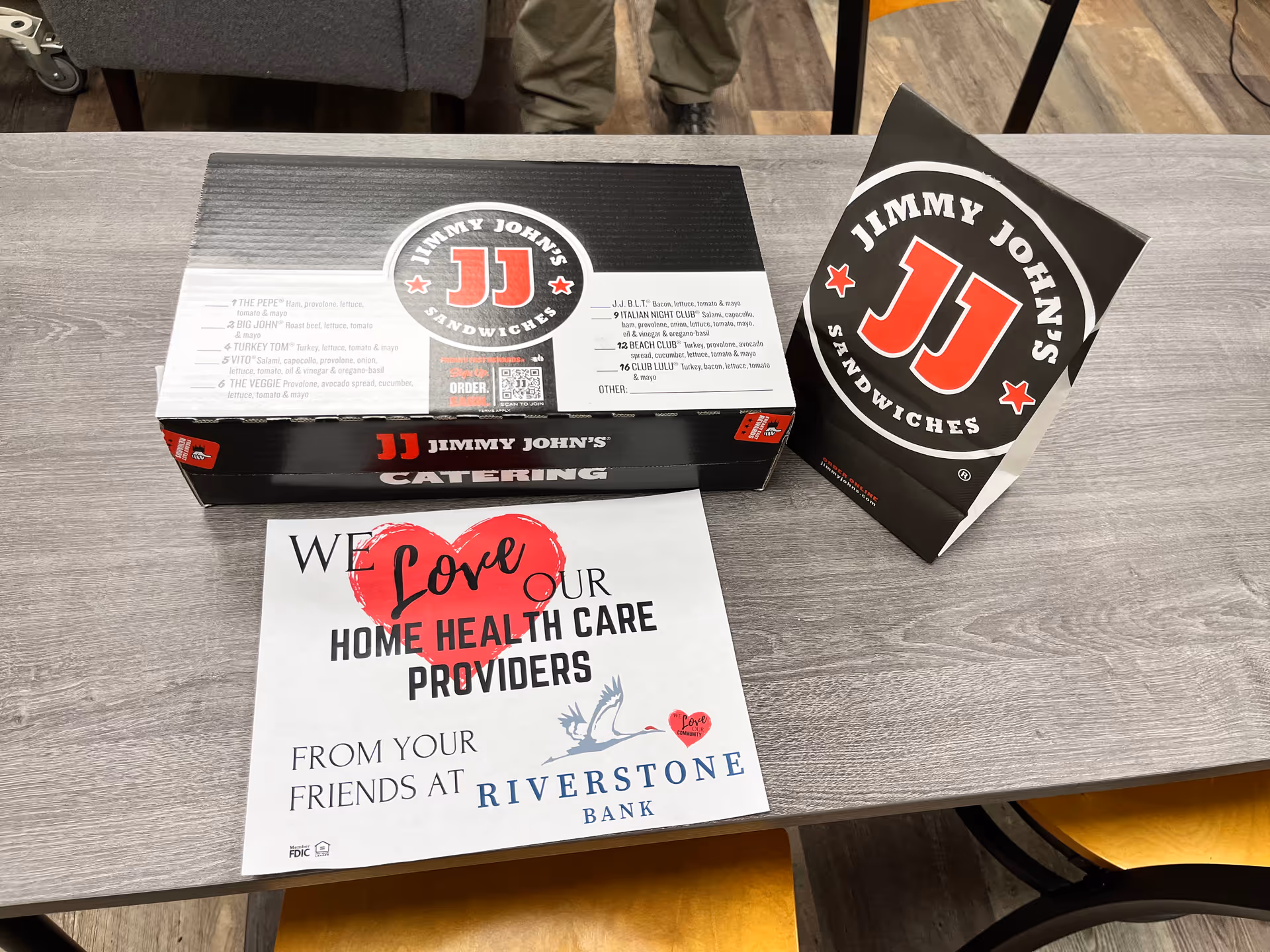 Jimmy John's catering boxes and a sign for home health care providers on a table.