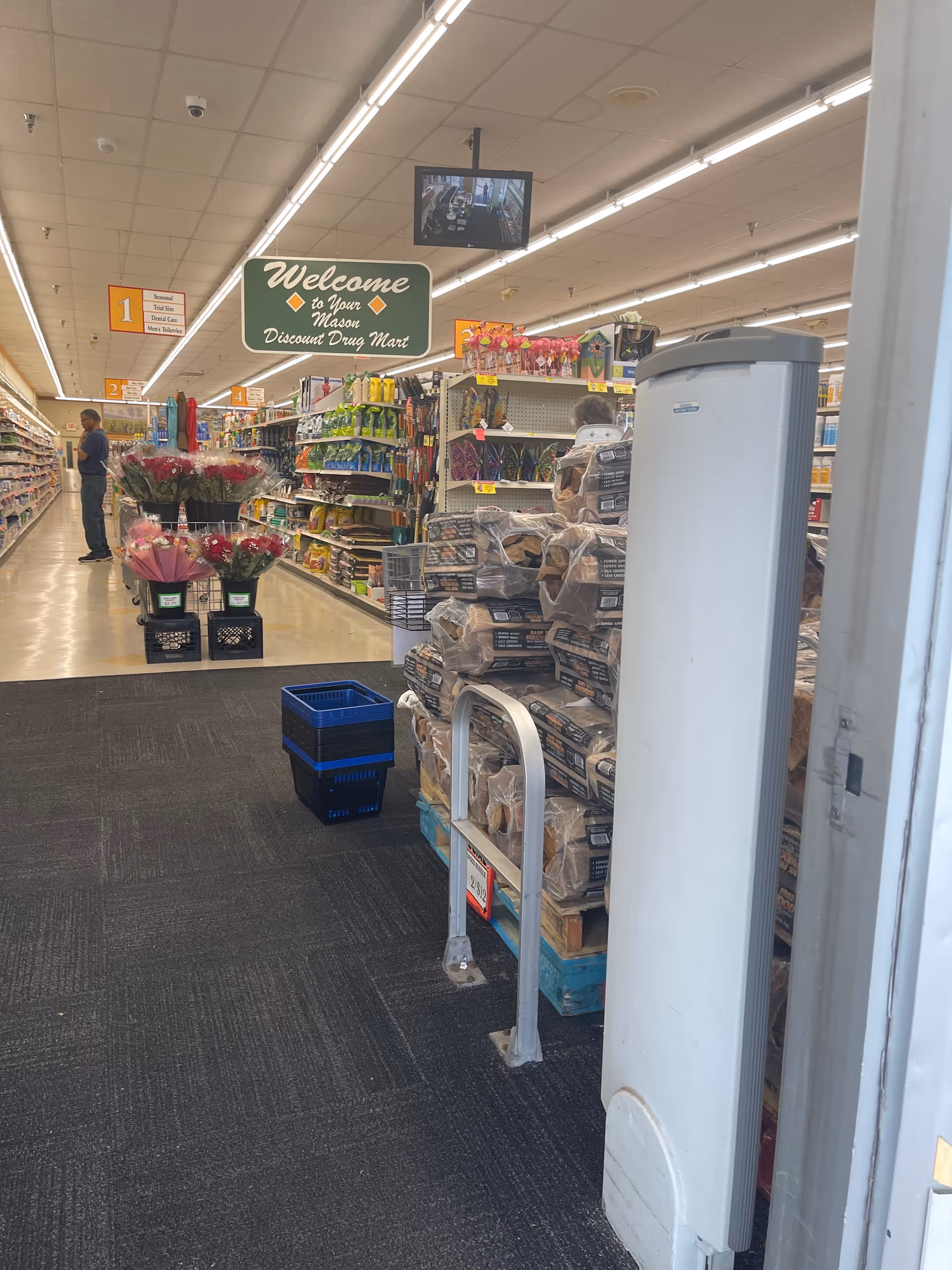 Inside Discount Drug Mart: shelves stocked with products, flowers, and a blue crate near the aisle.