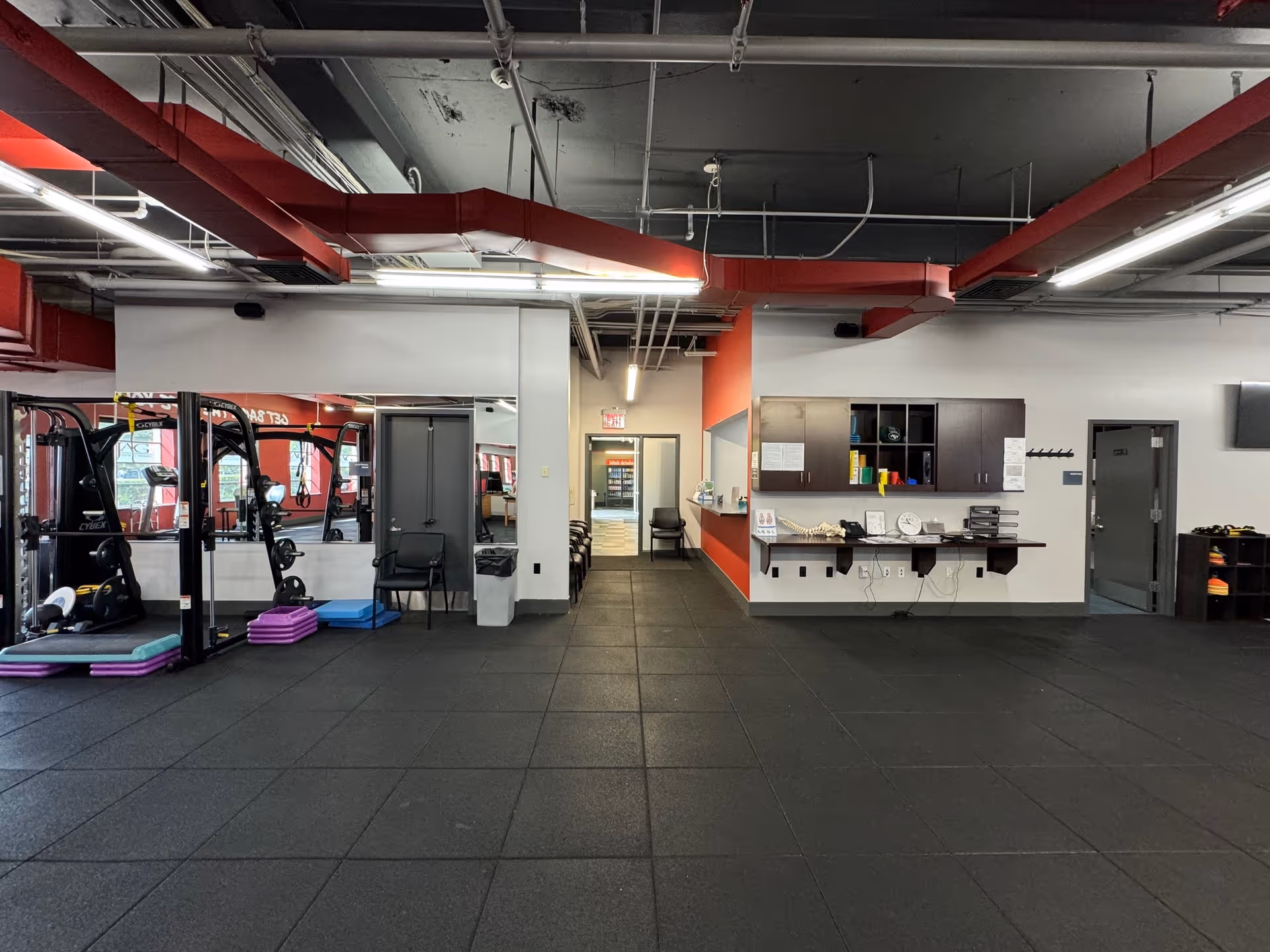Interior of a fitness gym in a senior facility with weight machines and a reception area.