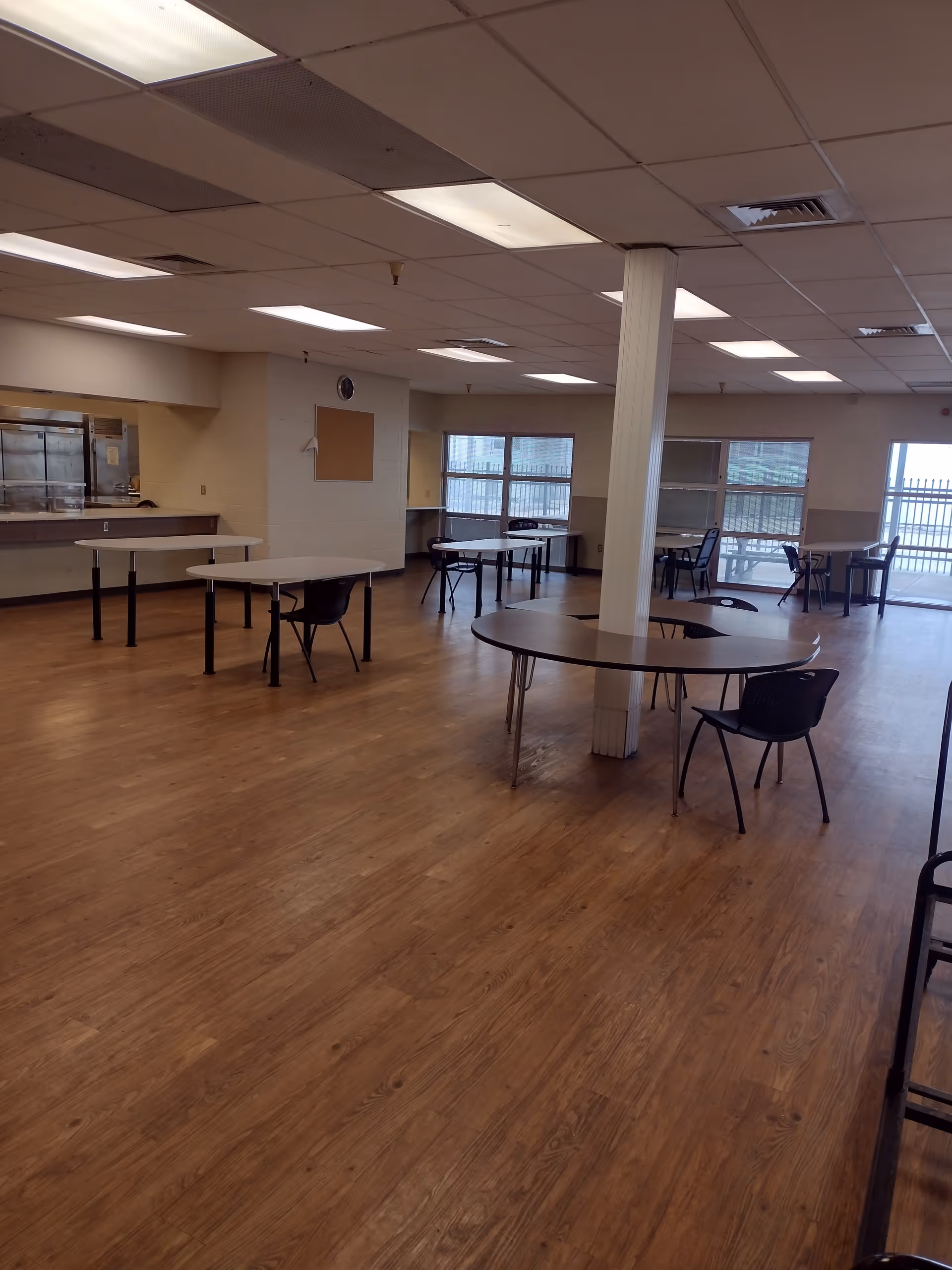 Empty dining hall with round tables and chairs inside a senior living facility.