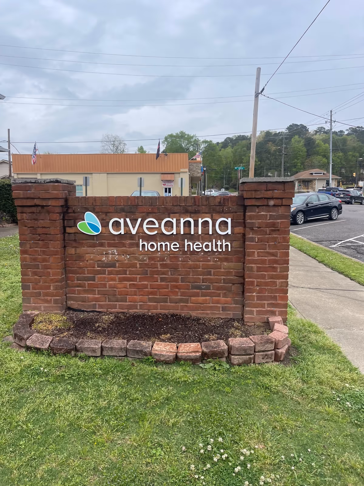 Brick Aveanna Home Health sign with parking lot behind.