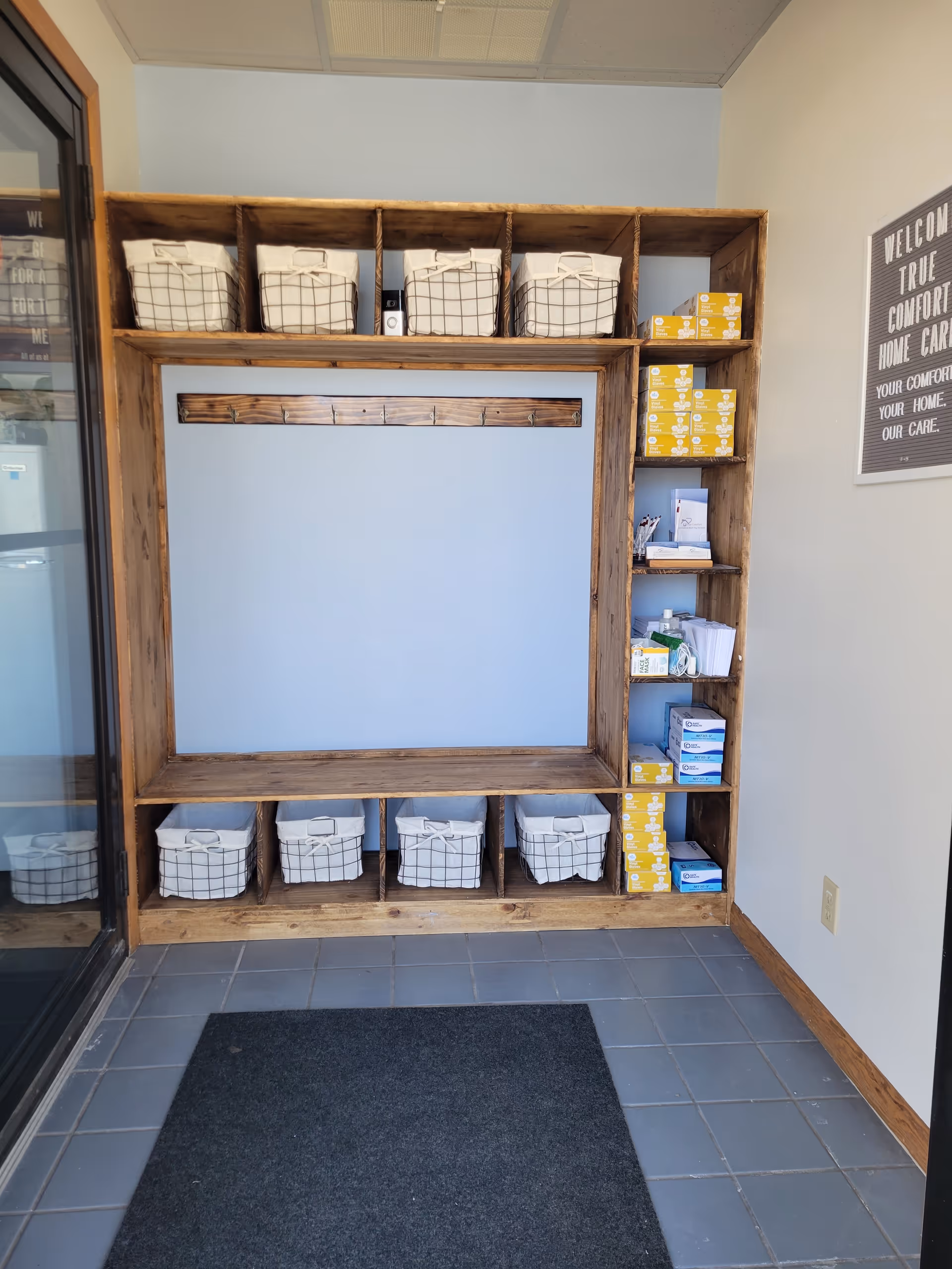 Wooden shelving unit with baskets and medical boxes in a facility hallway.