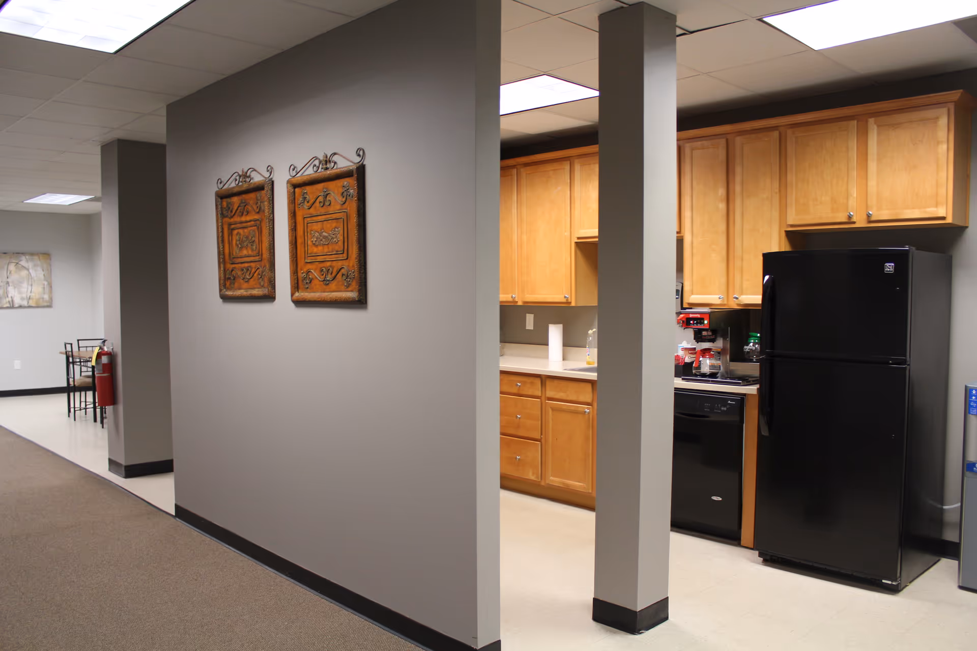 Interior view of a senior care kitchenette with wooden cabinets and black appliances.