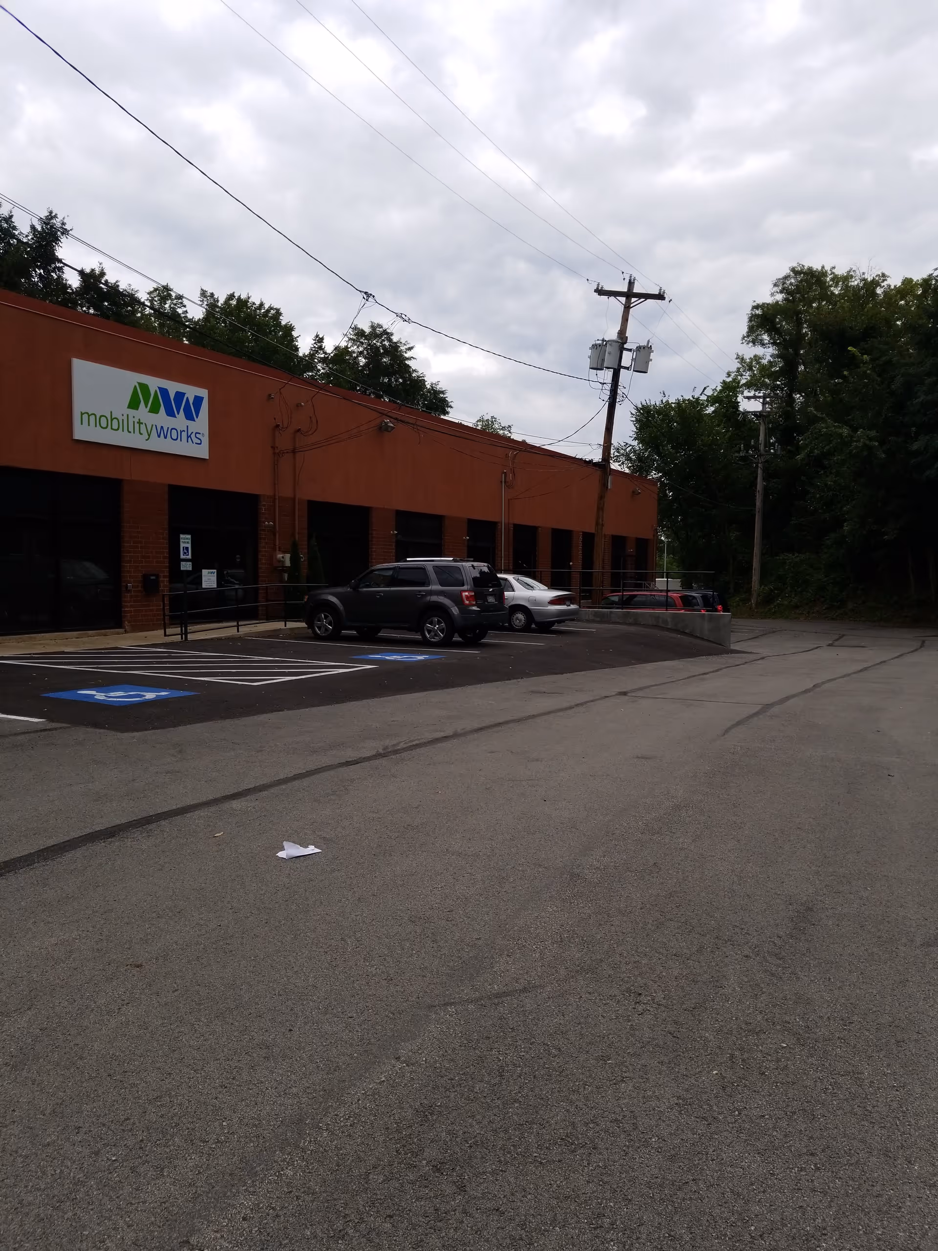 Exterior view of MobilityWorks building with parking lot and several cars.
