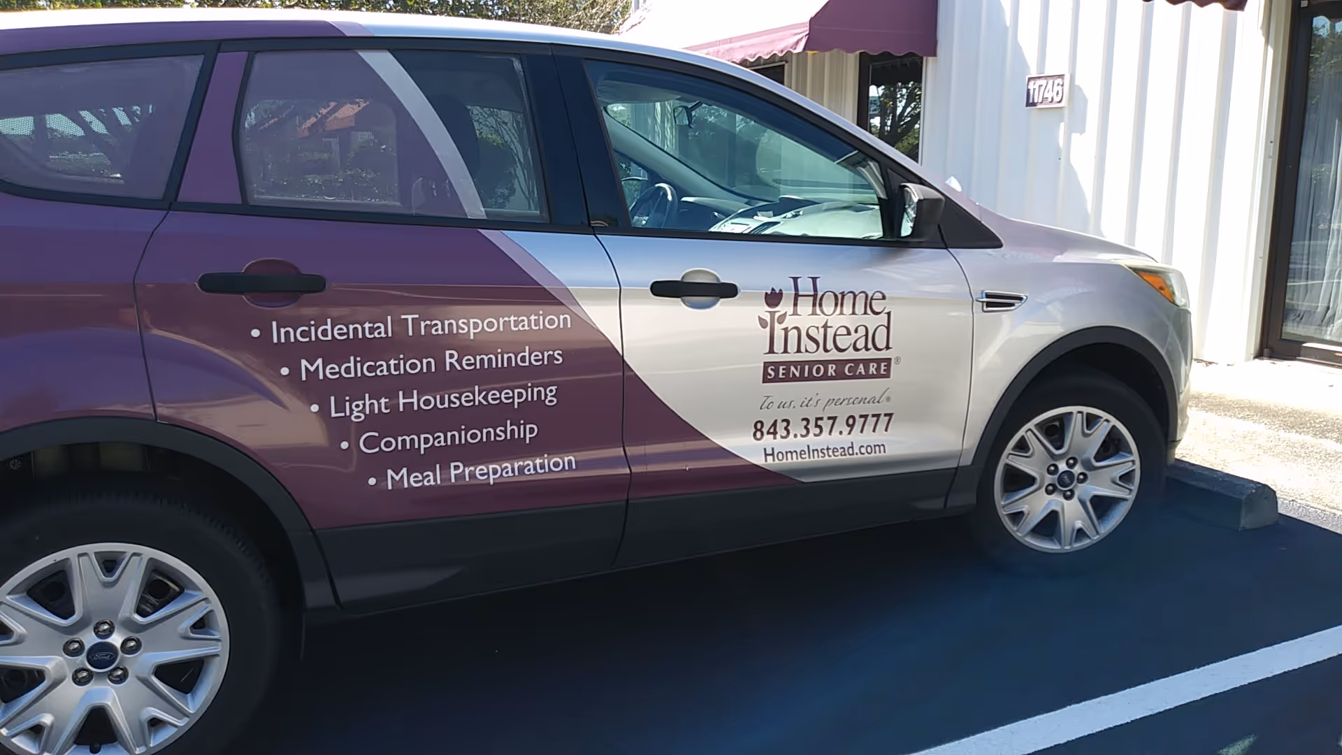 Purple Home Instead senior care van parked outside a building entrance.