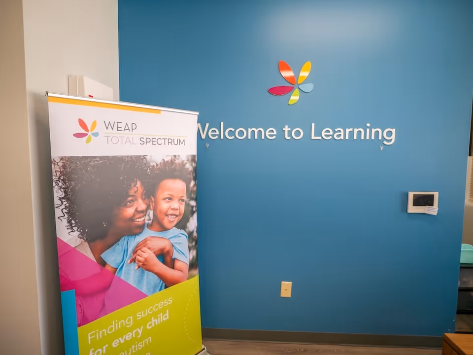 Blue interior wall with Welcome to Learning sign and a colorful banner on the left.