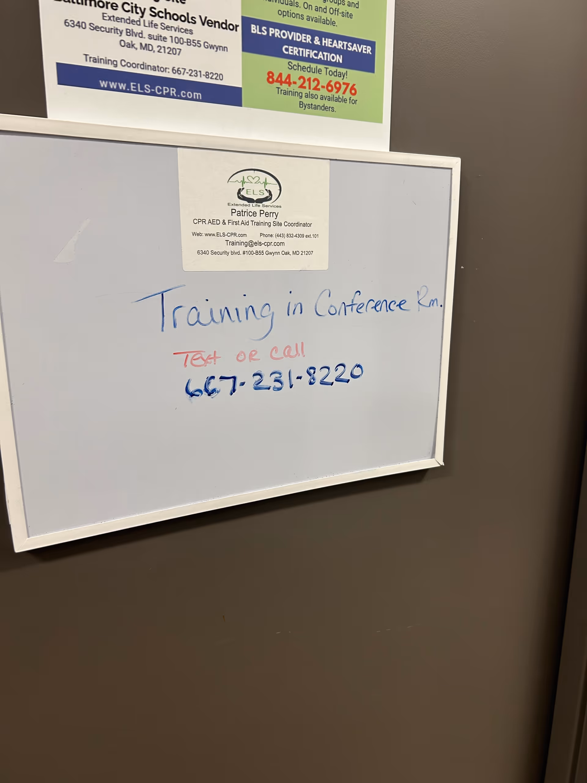 Whiteboard with training note and posted flyers on a brown wall.