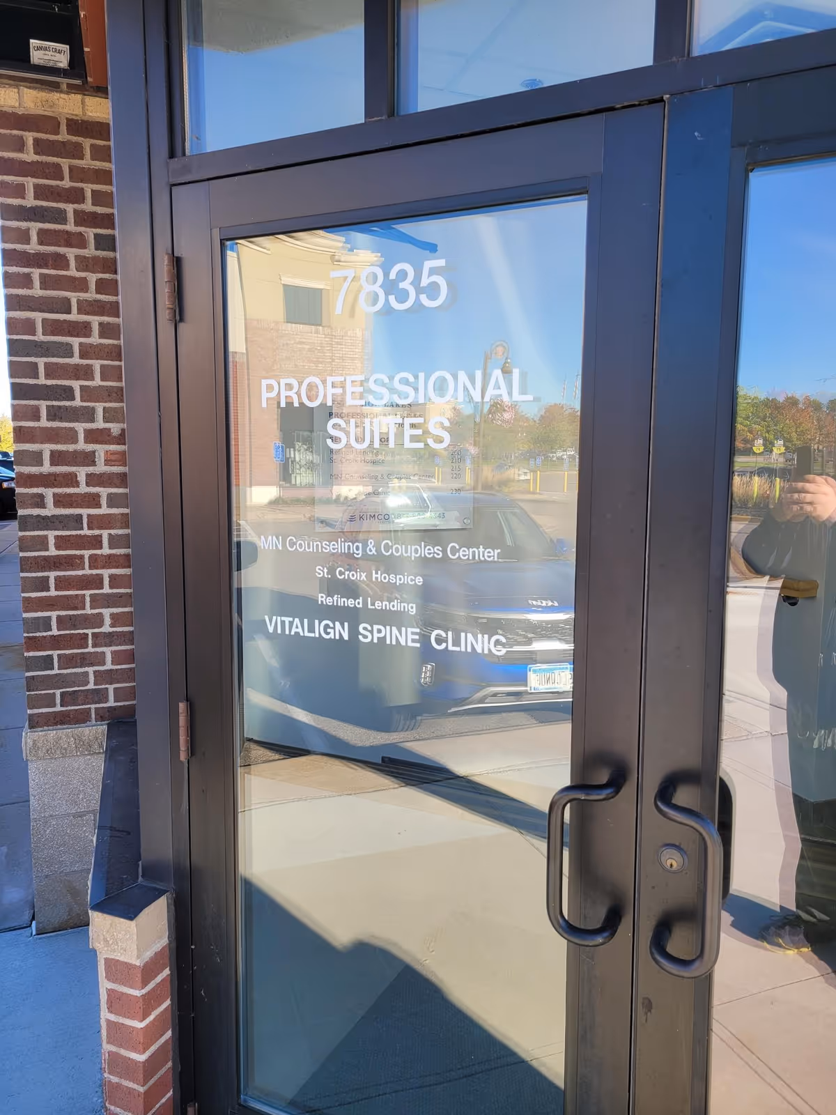 Exterior glass entrance door with signage for Professional Suites and St. Croix Hospice