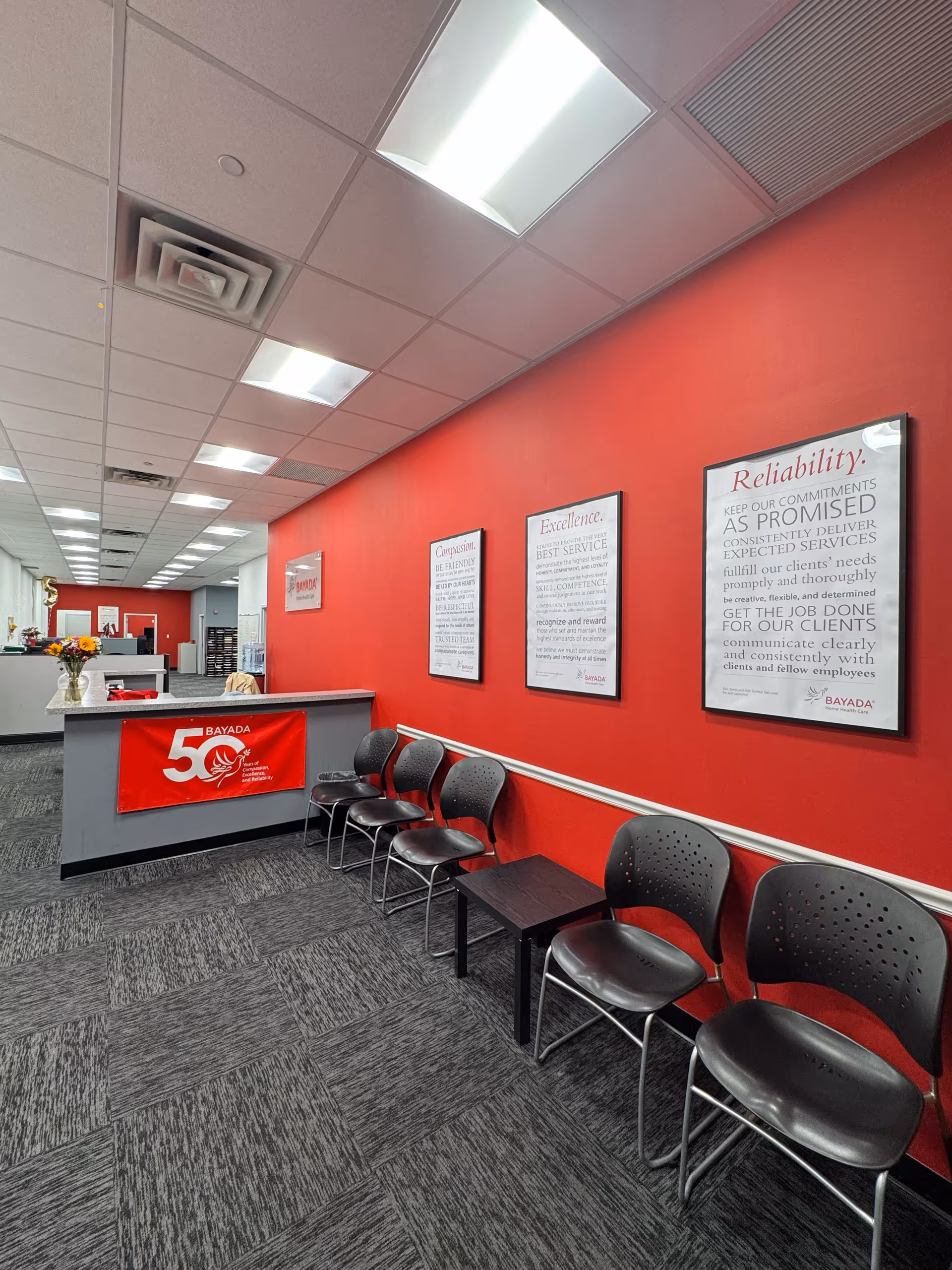 Red-walled reception area with chairs, a front desk, and framed posters.