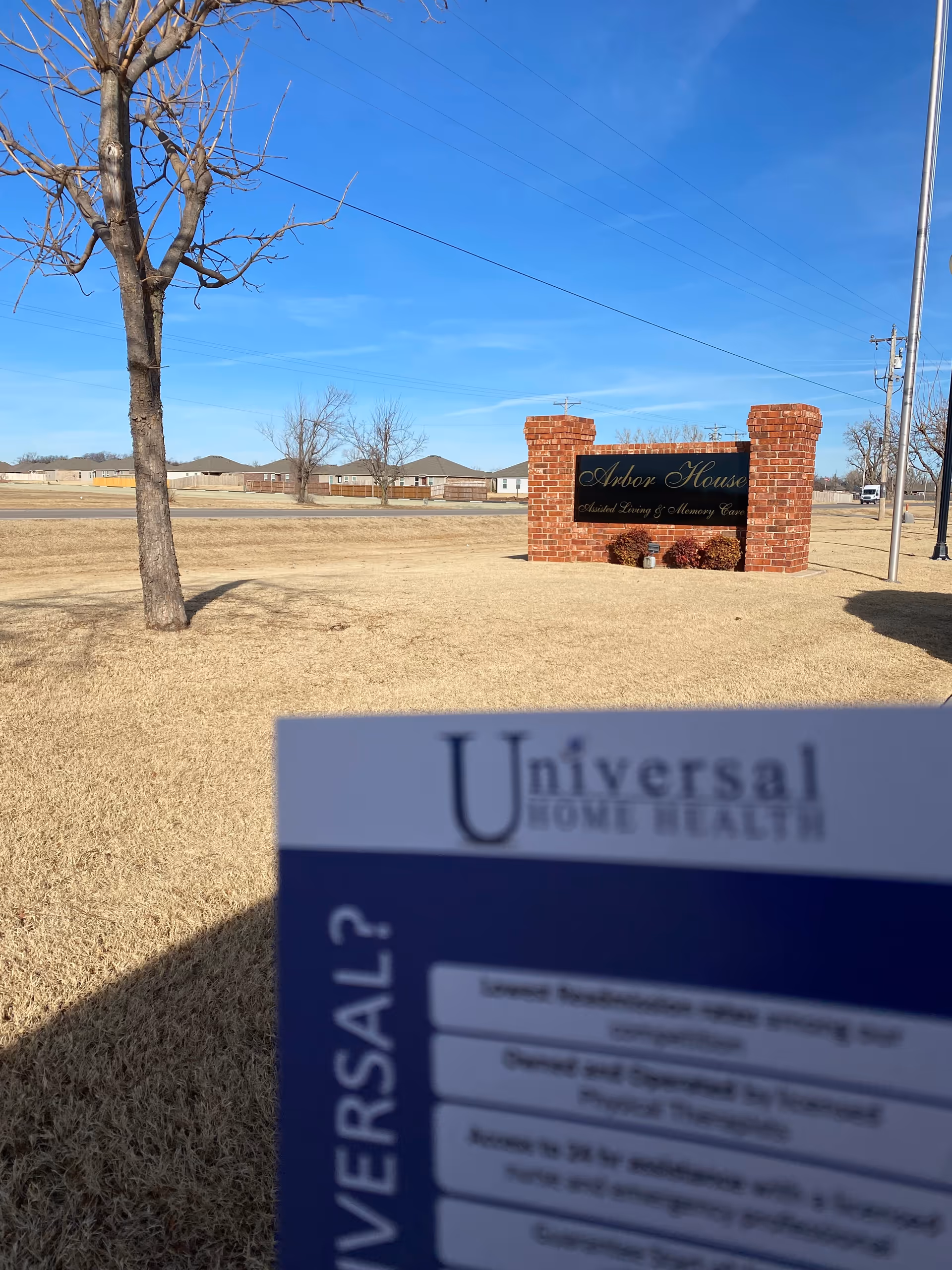 Outdoor scene with a brick Arbor House sign and a Universal Home Health card in foreground.