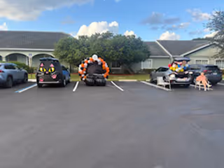 Three decorated vehicles with balloon arches parked in a parking lot outside a senior living facility.