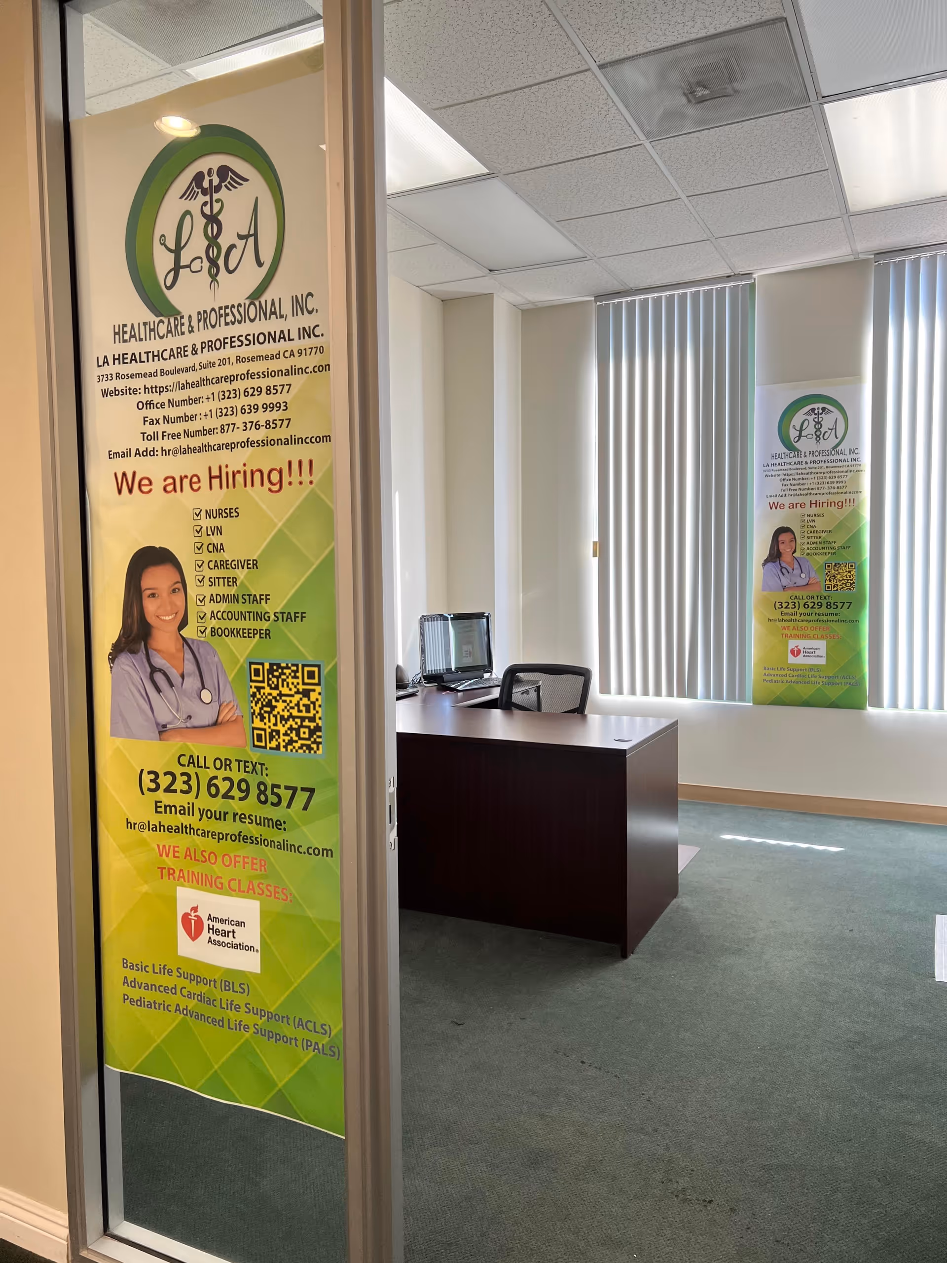 Reception area in a healthcare office with banners, desk, and window blinds.