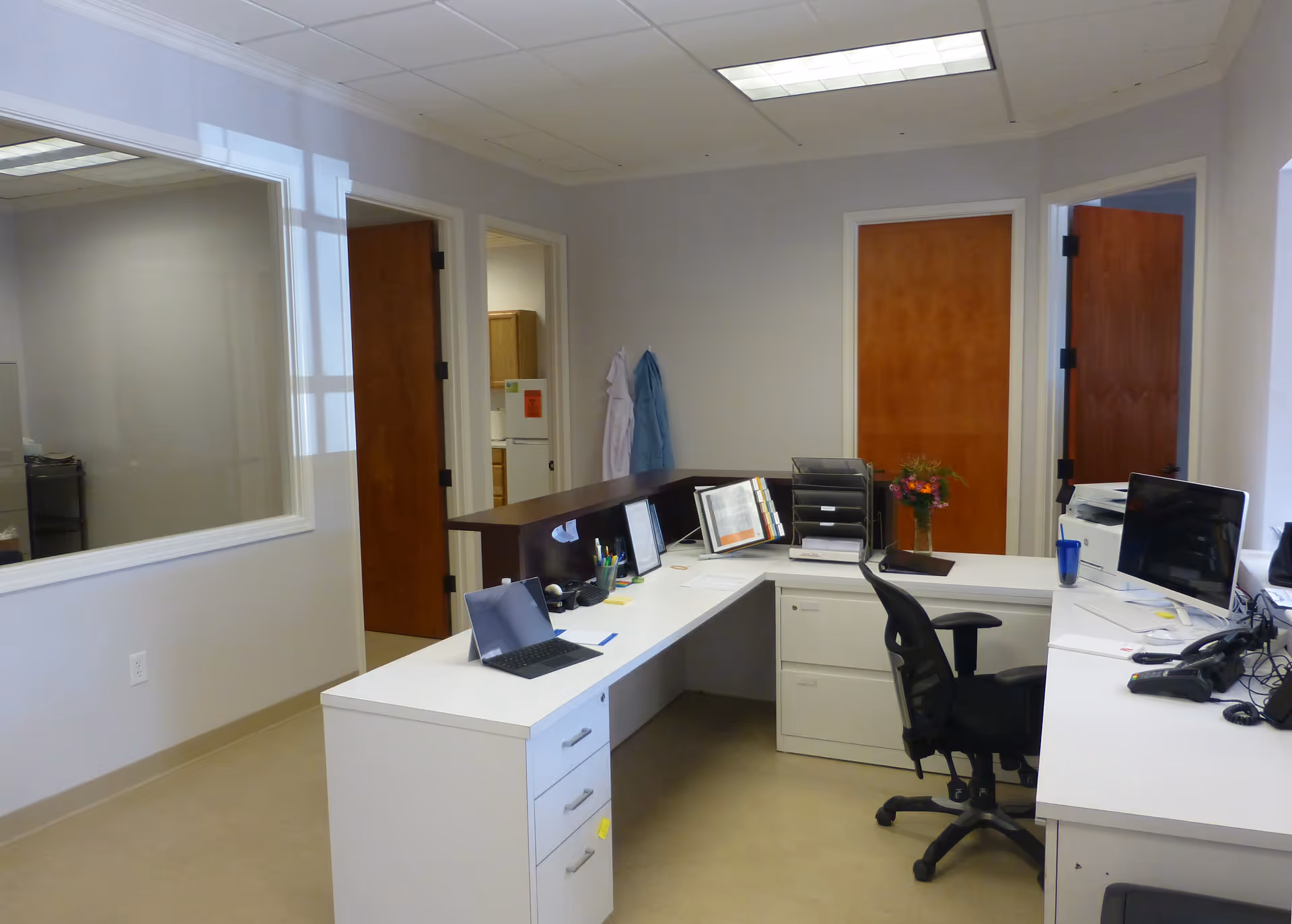 L-shaped white desks with computers in a tidy office area.