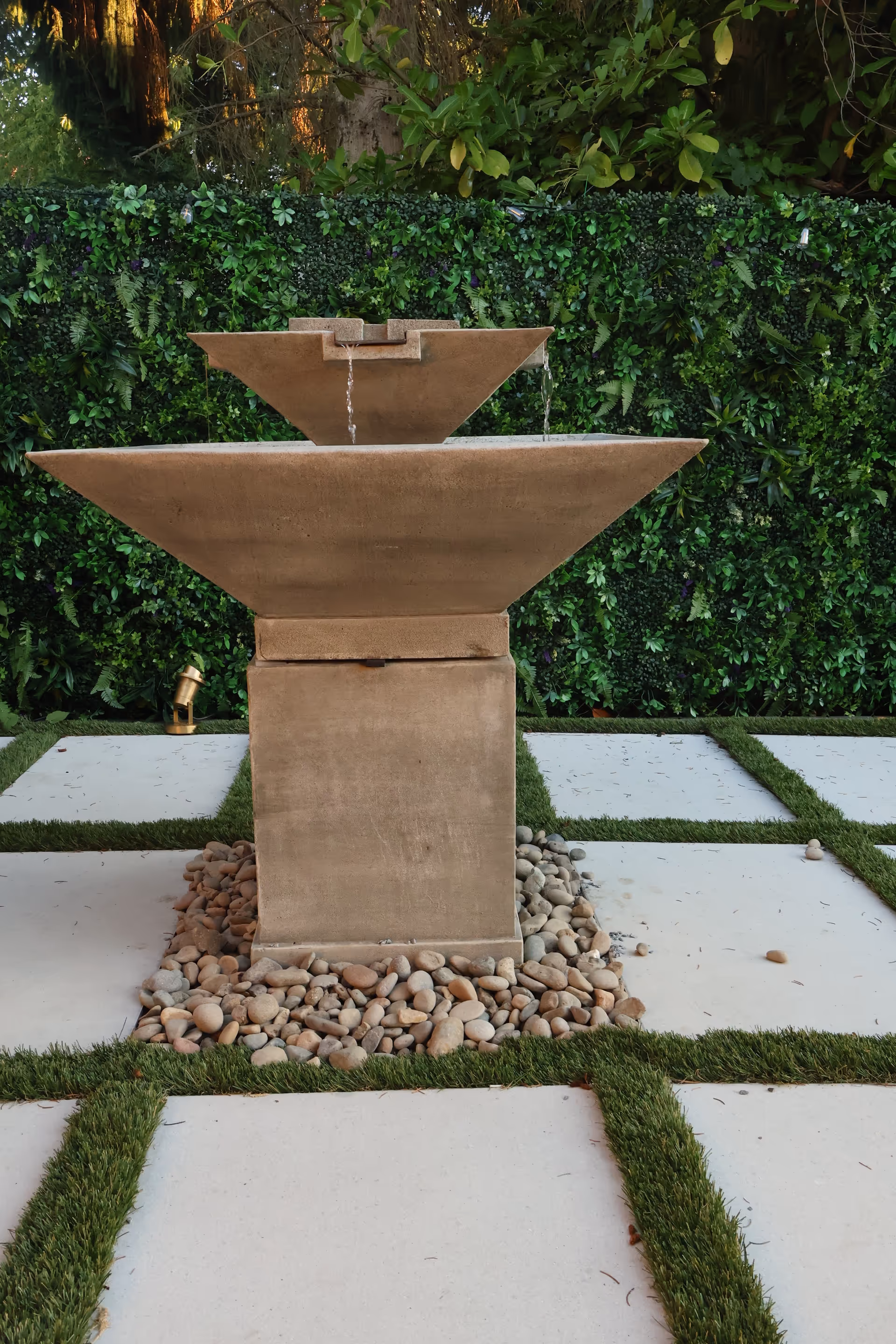 Outdoor courtyard fountain with tiered stone basins and surrounding greenery.