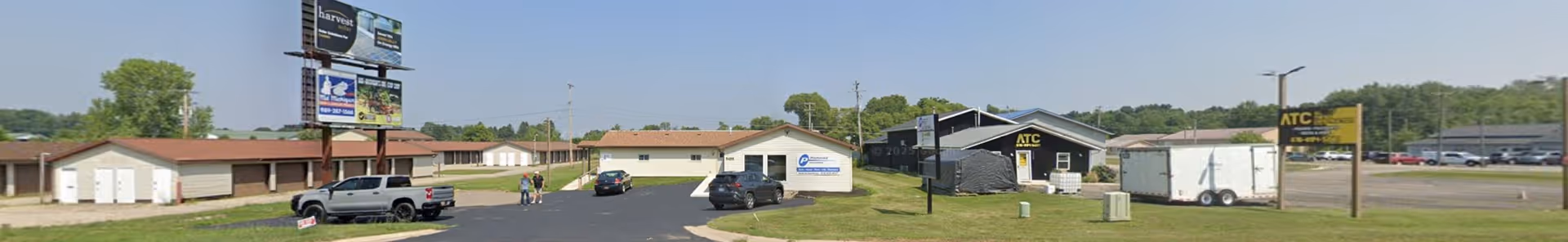 Wide exterior view of a senior living facility with low buildings and parked cars.
