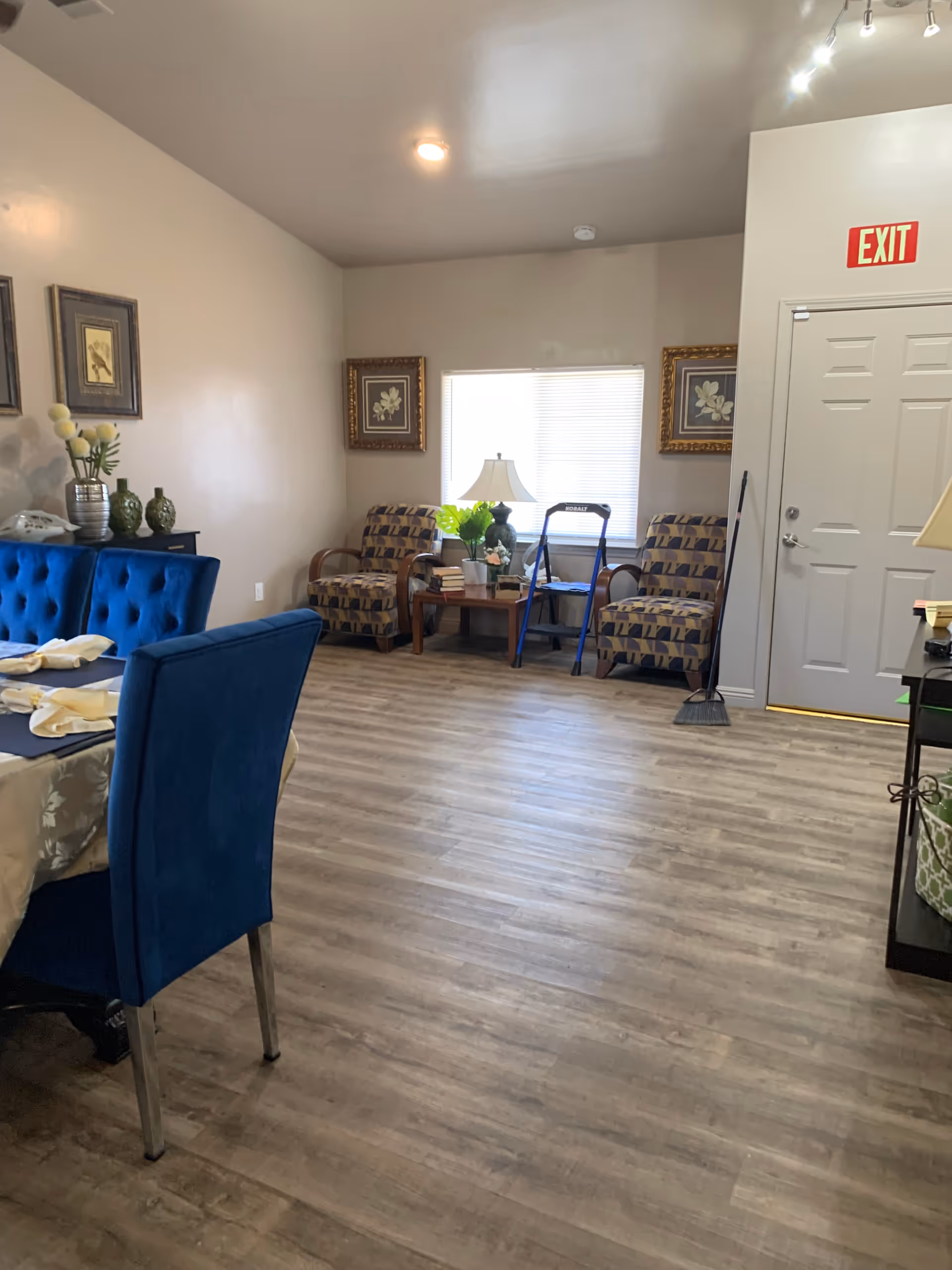 Cozy senior living dining area with blue chairs, patterned armchairs, and a window.