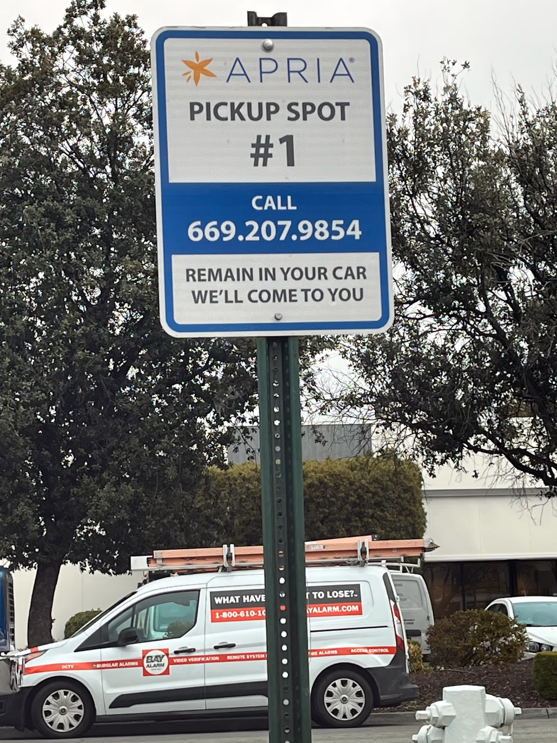 Outdoor Apria pickup sign in a parking lot with a service van.