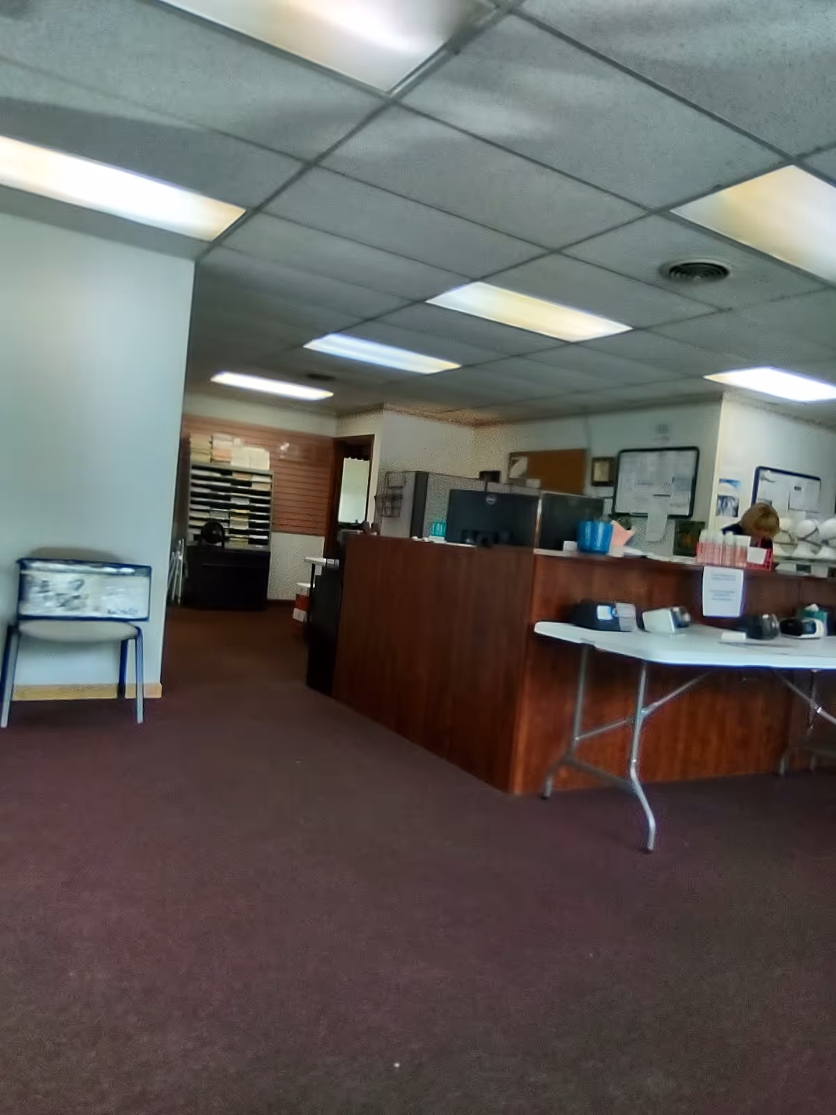 Interior of a senior facility lobby with a wooden front desk and fluorescent ceiling lights