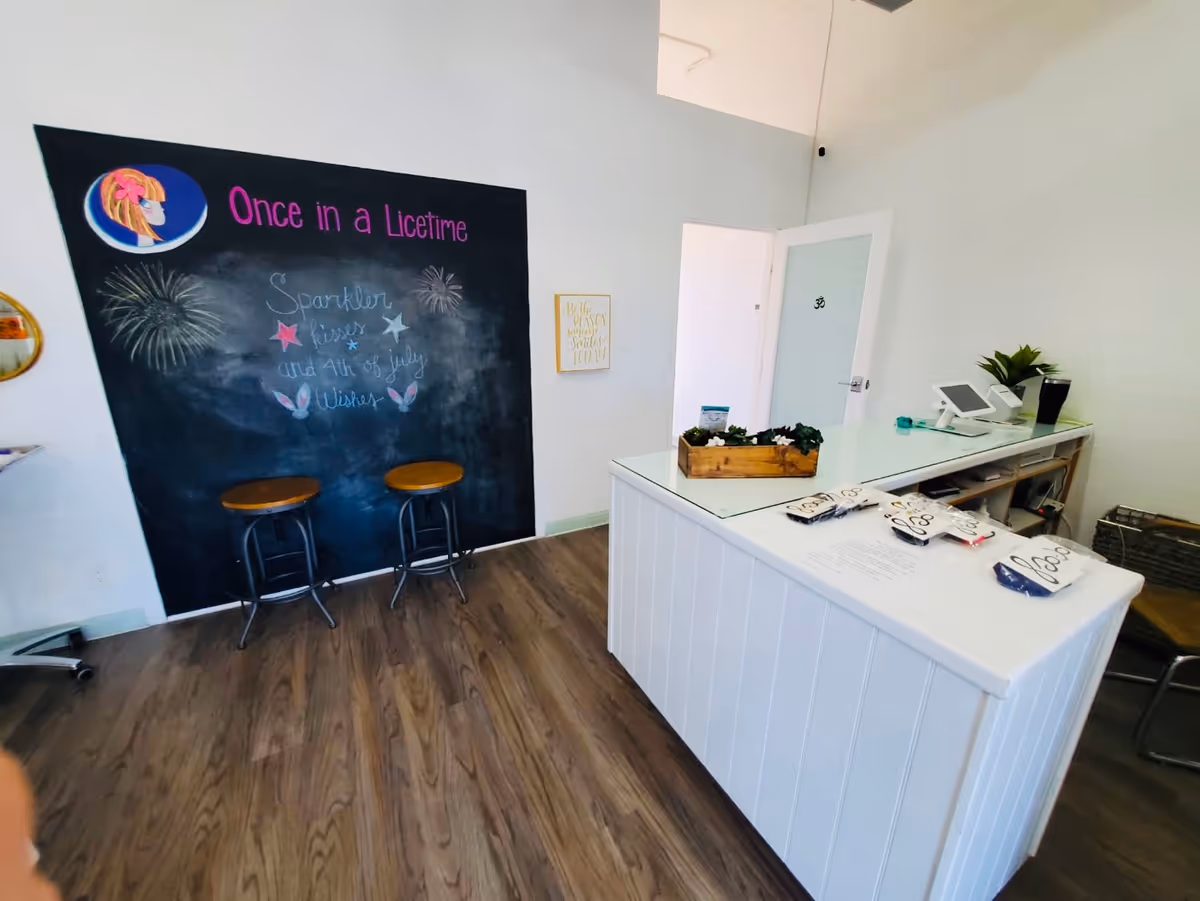 Reception area with chalkboard wall reading 'Once in a Licetime' and a white front desk.