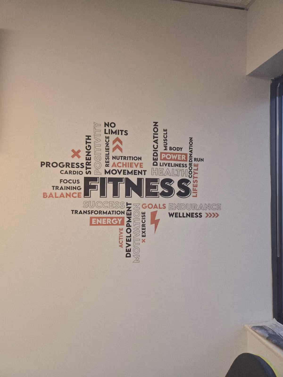 Interior wall features a large FITNESS word art mural with fitness terms.