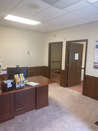 Reception desk in a neutral-toned interior with brochures and doorway to back offices.