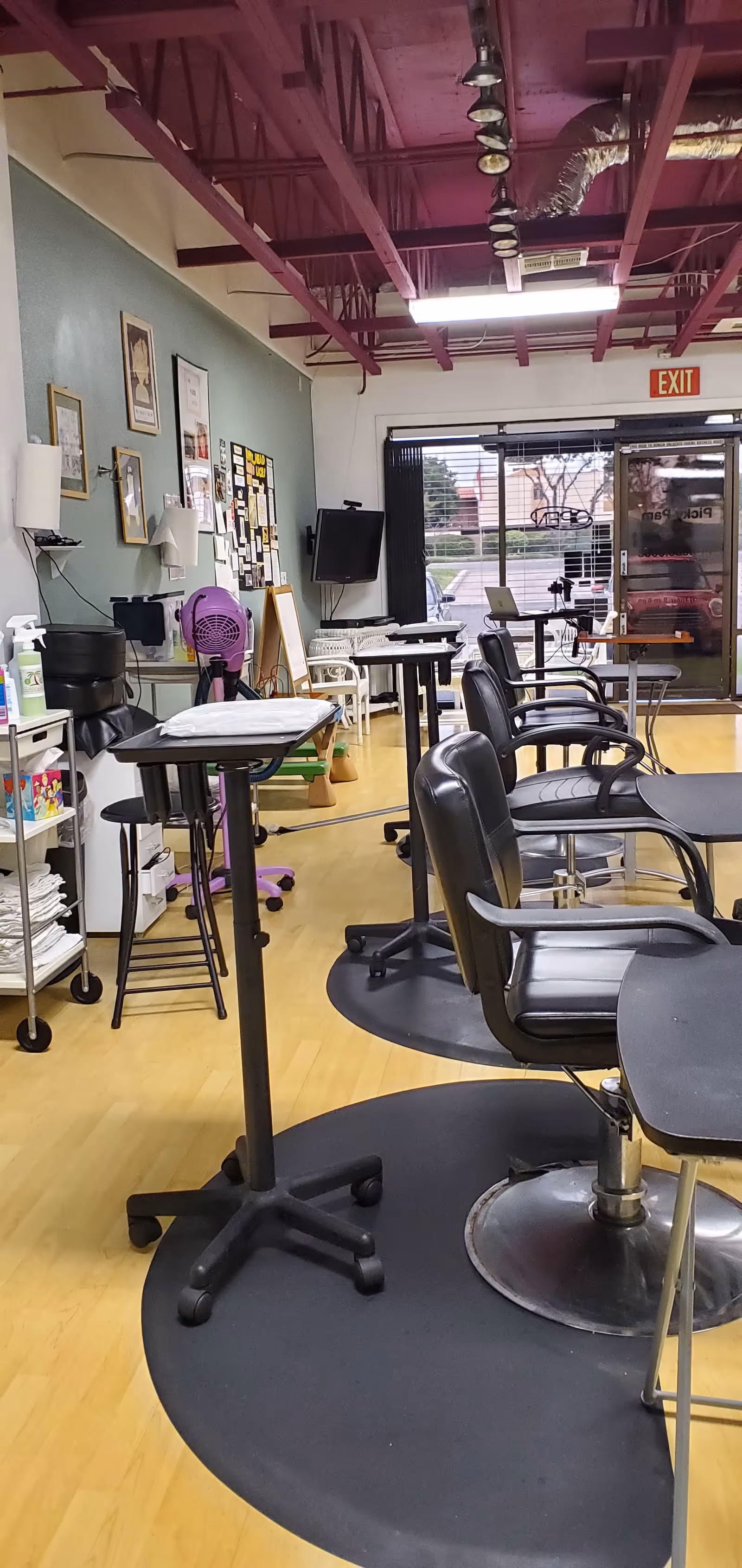 Interior salon area with multiple styling chairs, carts, and equipment.