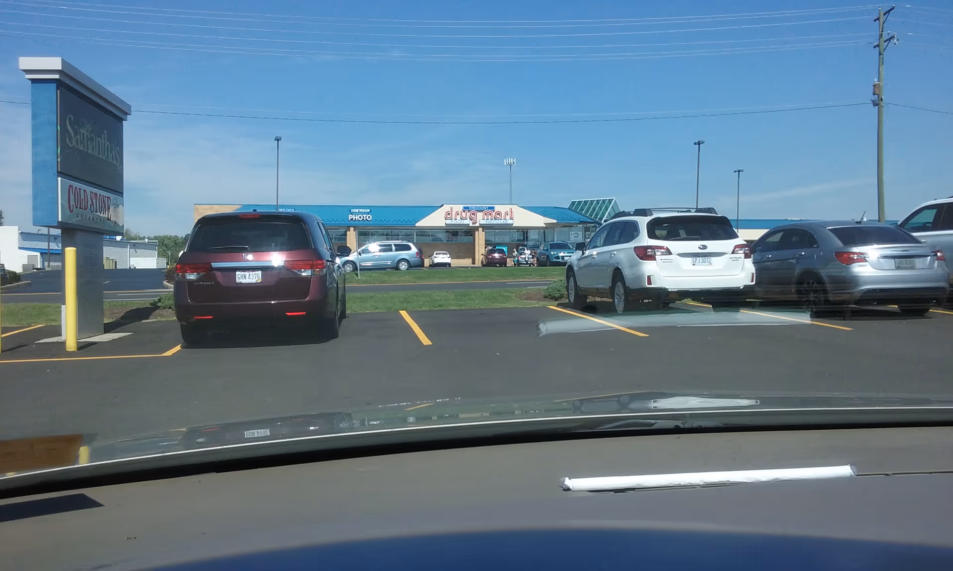 Parking lot view of Discount Drug Mart storefront with several parked cars.