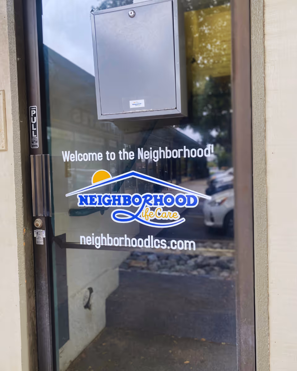 Glass door entry with Neighborhood Life Care logo and a welcome message.